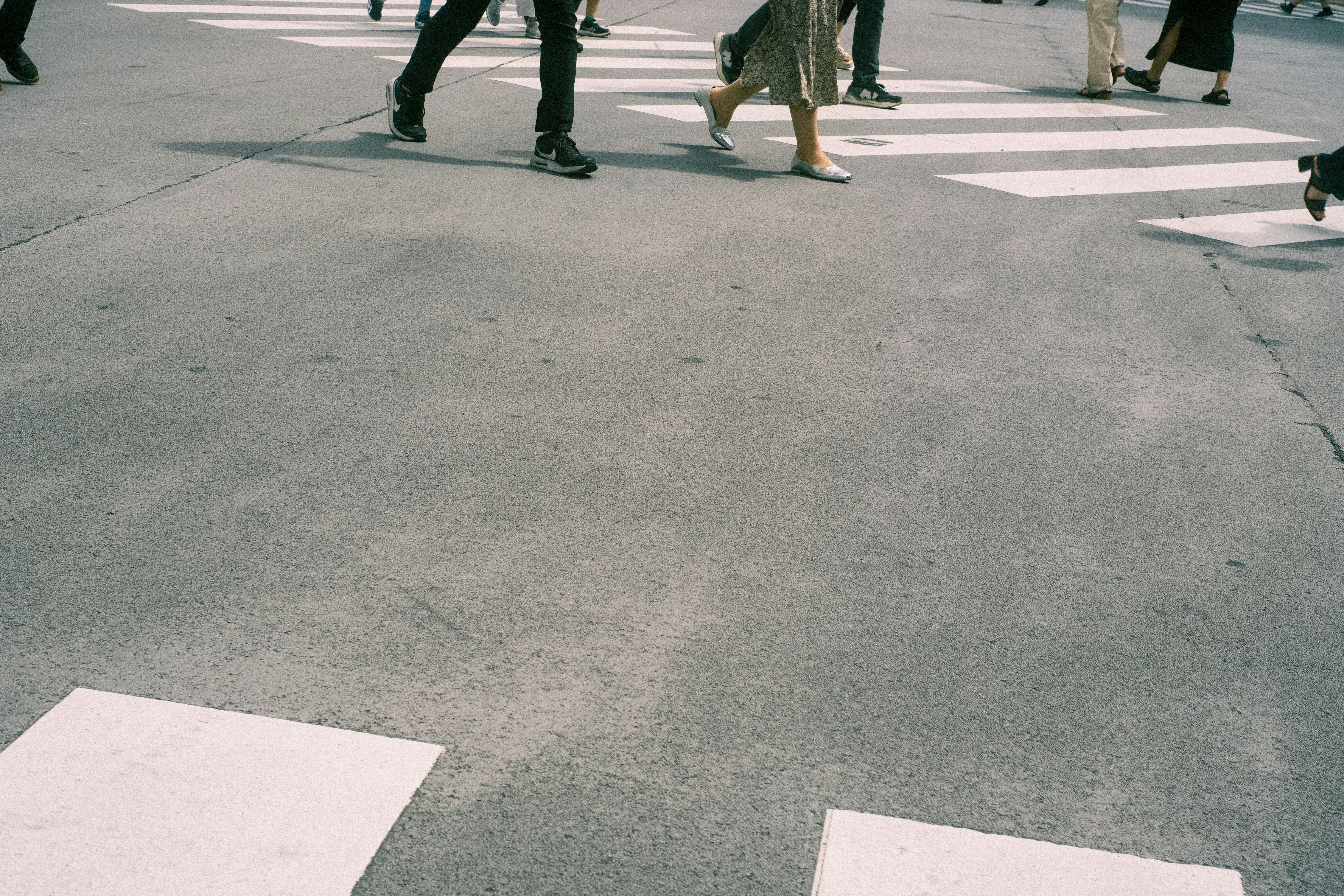 pies de personas caminando sobre un paso de peatones