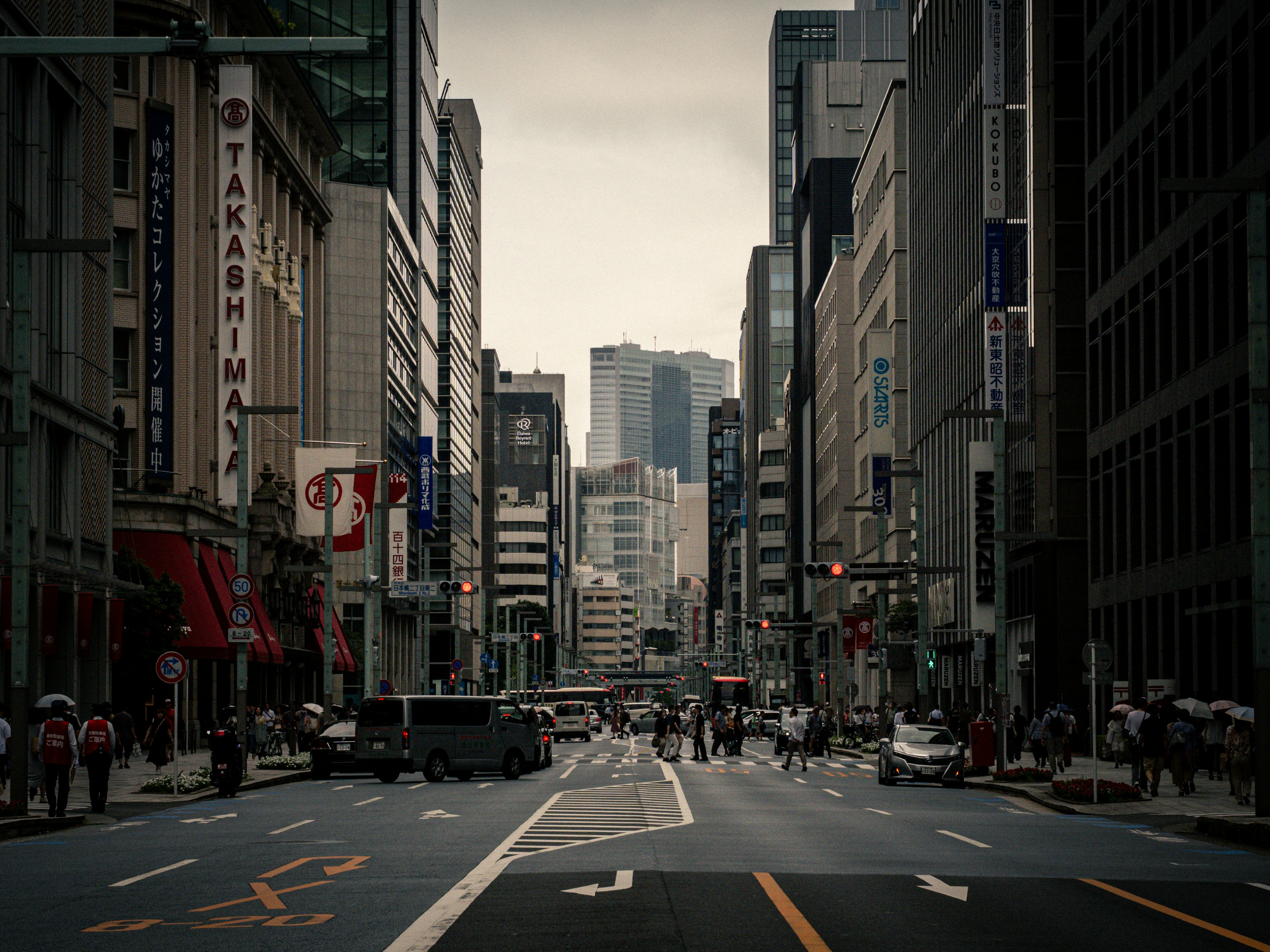 陰天的市中心大道，車輛與行人穿行