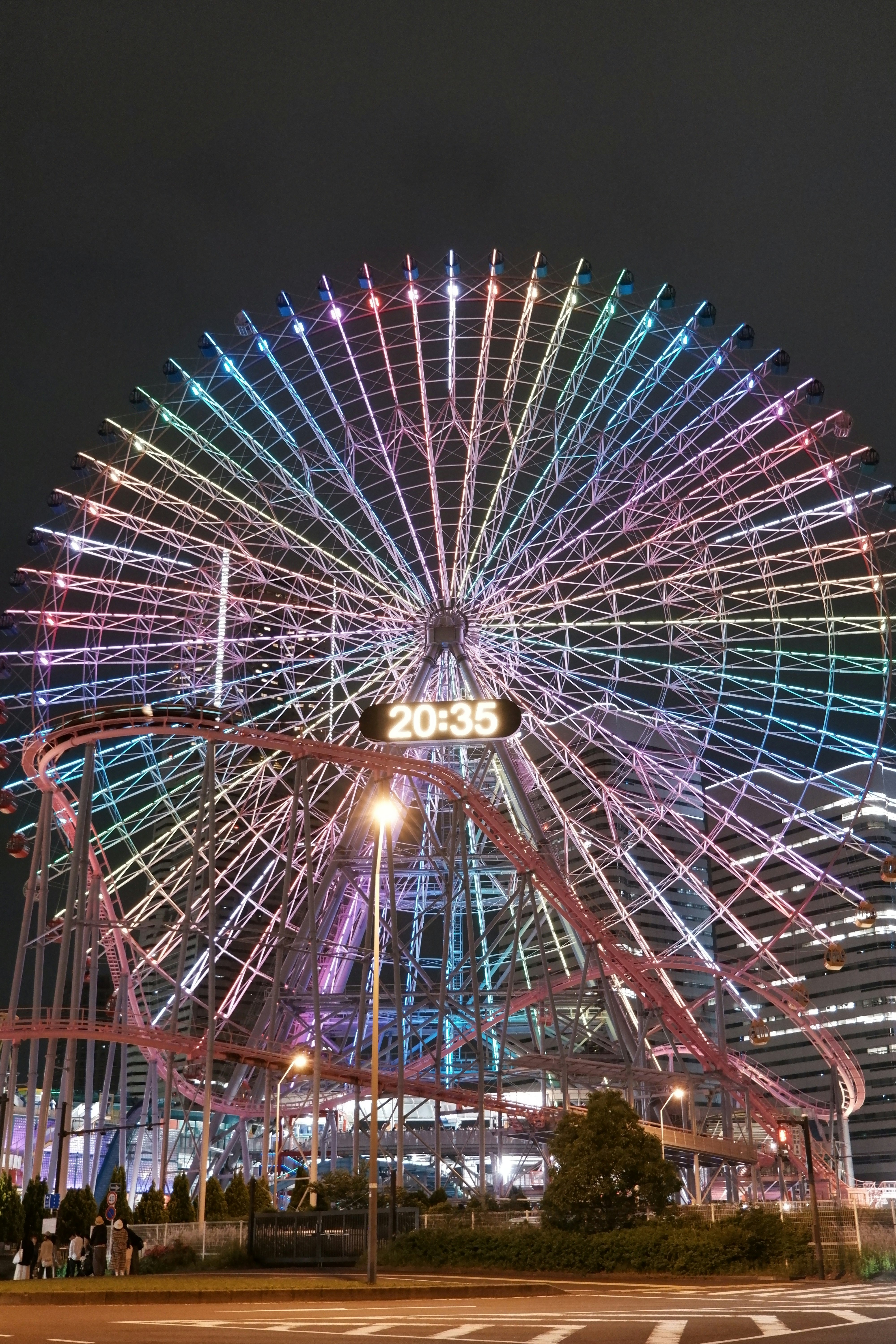 観覧車のイルミネーションが夜空に広がる遊園地の通り