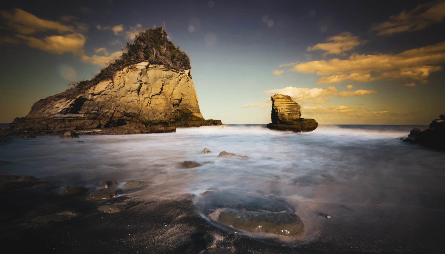 Costa escénica con olas suaves golpeando formaciones rocosas distintivas