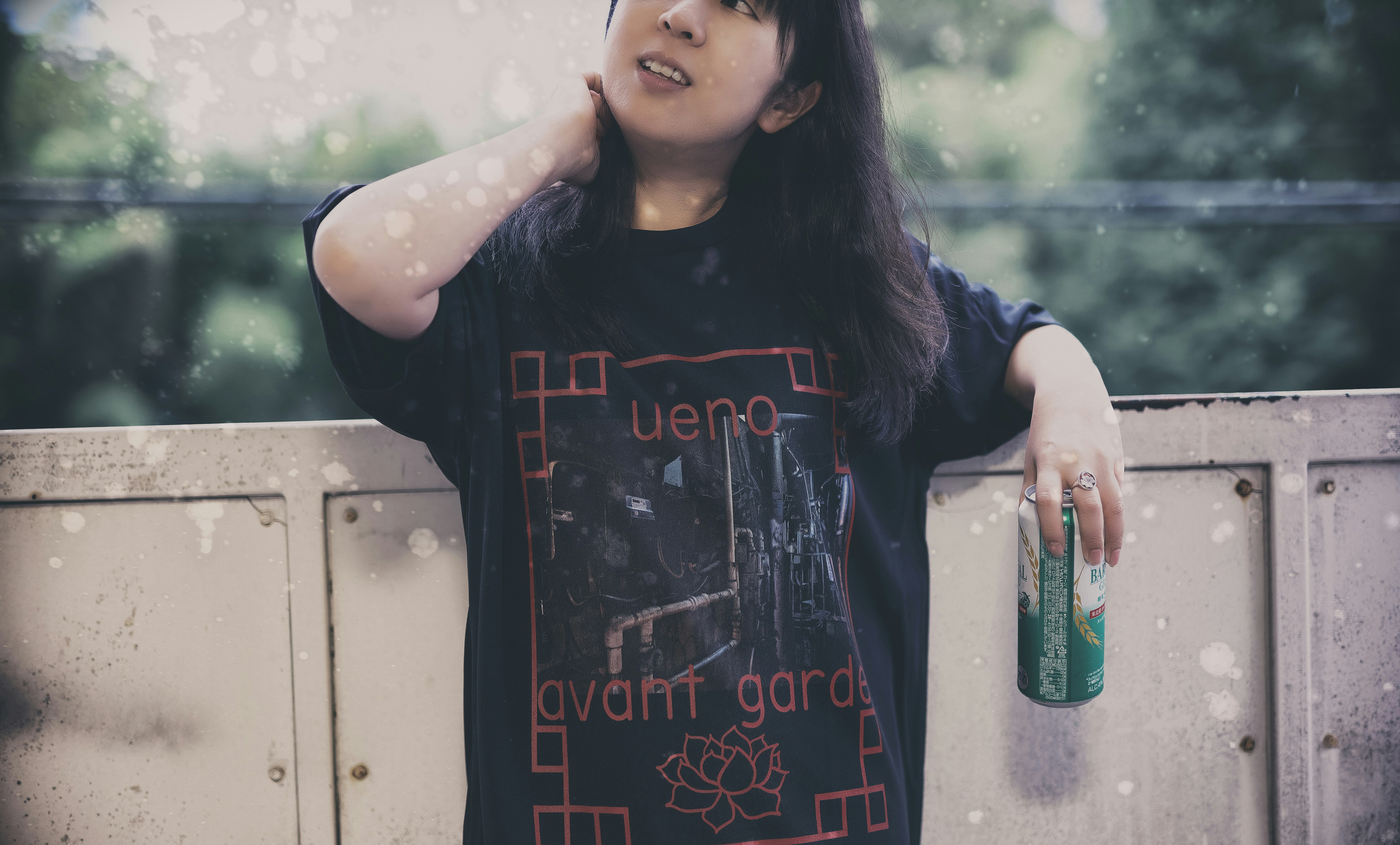 Woman leaning by a wall wearing a “Ueno avant garde” T-shirt