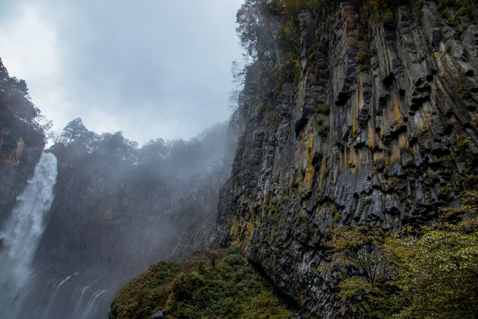Felsige Klippe in der Nähe eines Wasserfalls mit nebliger Atmosphäre