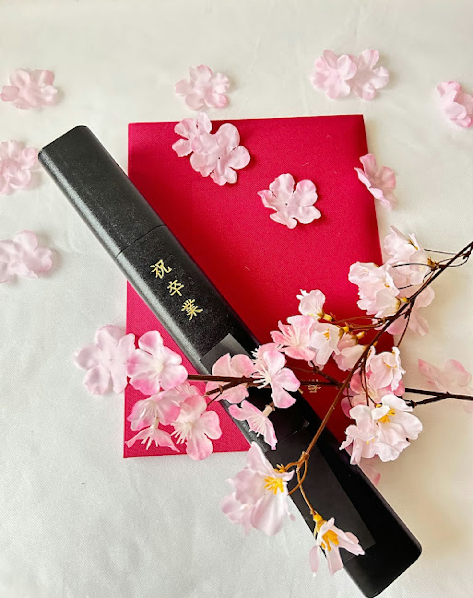Pennello di calligrafia su carta rossa con petali di ciliegio rosa