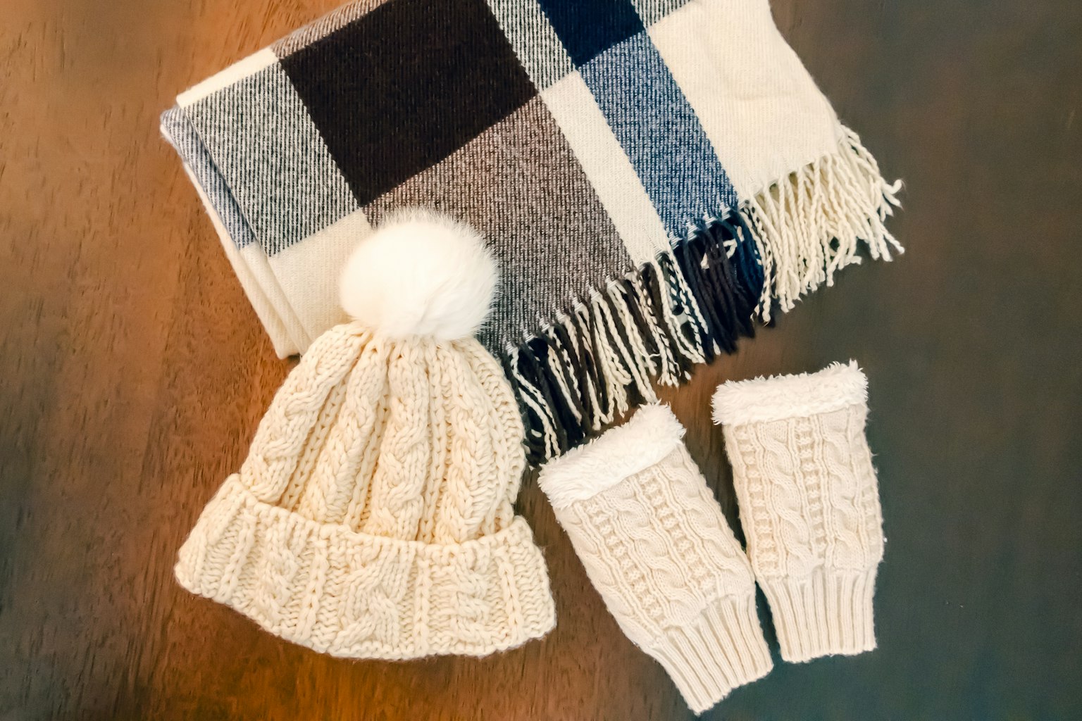 Weißer Strickhut und Handschuhe mit einer karierten Decke zusammen präsentiert