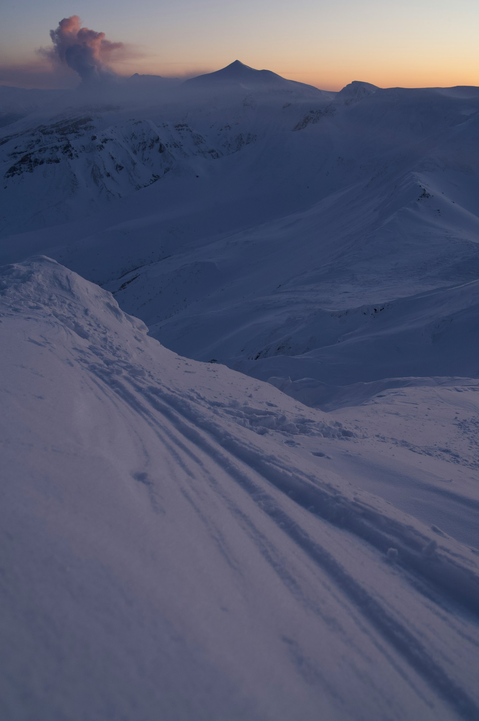 Snow-covered mountain range with a sunset sky
