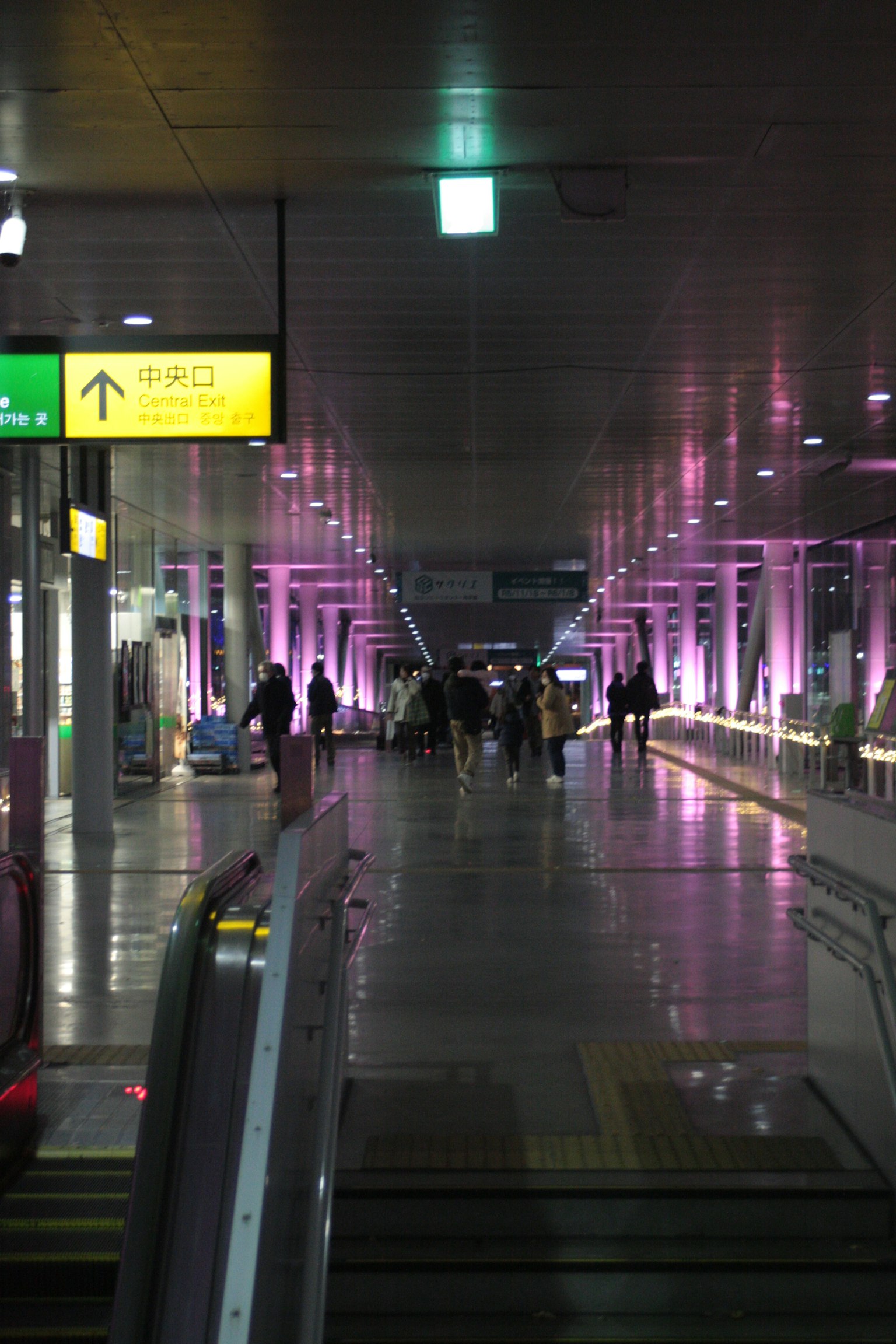 Pasillo de aeropuerto iluminado con luces moradas brillantes personas caminando