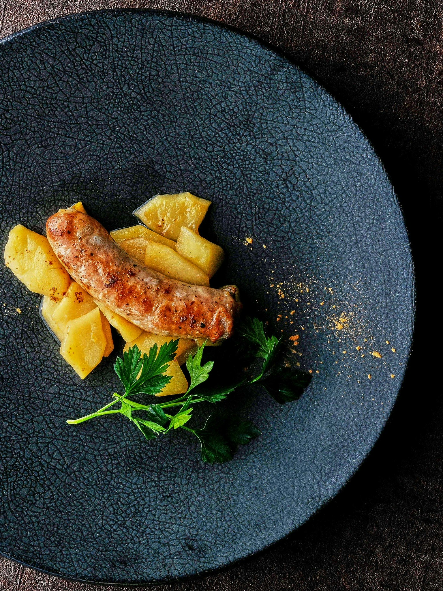 Un plato con salchicha y piña en un plato negro