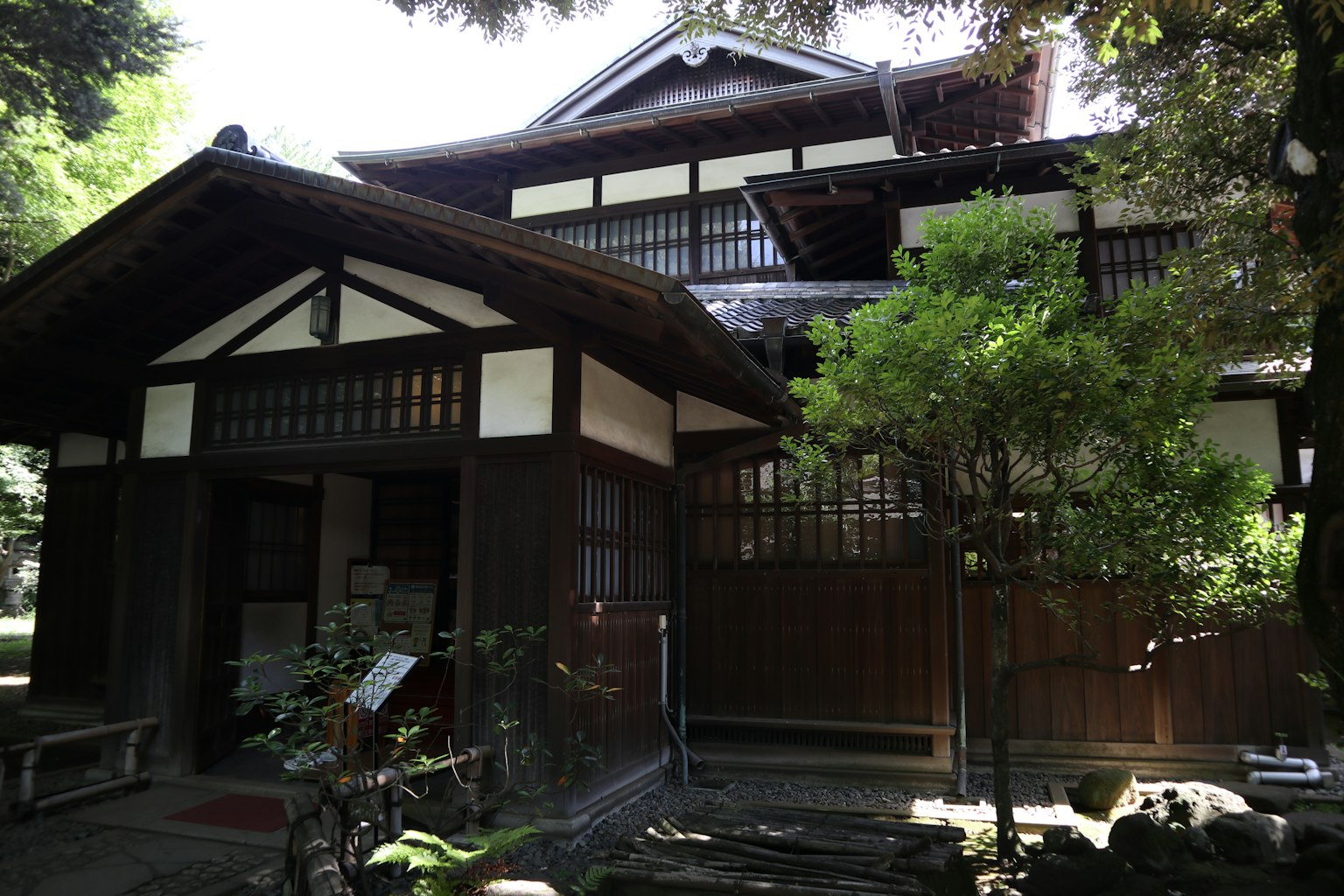 Eksterior rumah tradisional Jepang dengan vegetasi subur dan pohon-pohon
