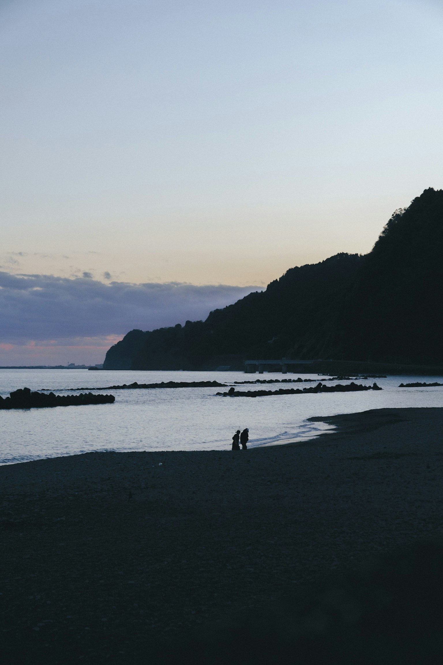 Silhouette of people walking on the beach at sunset