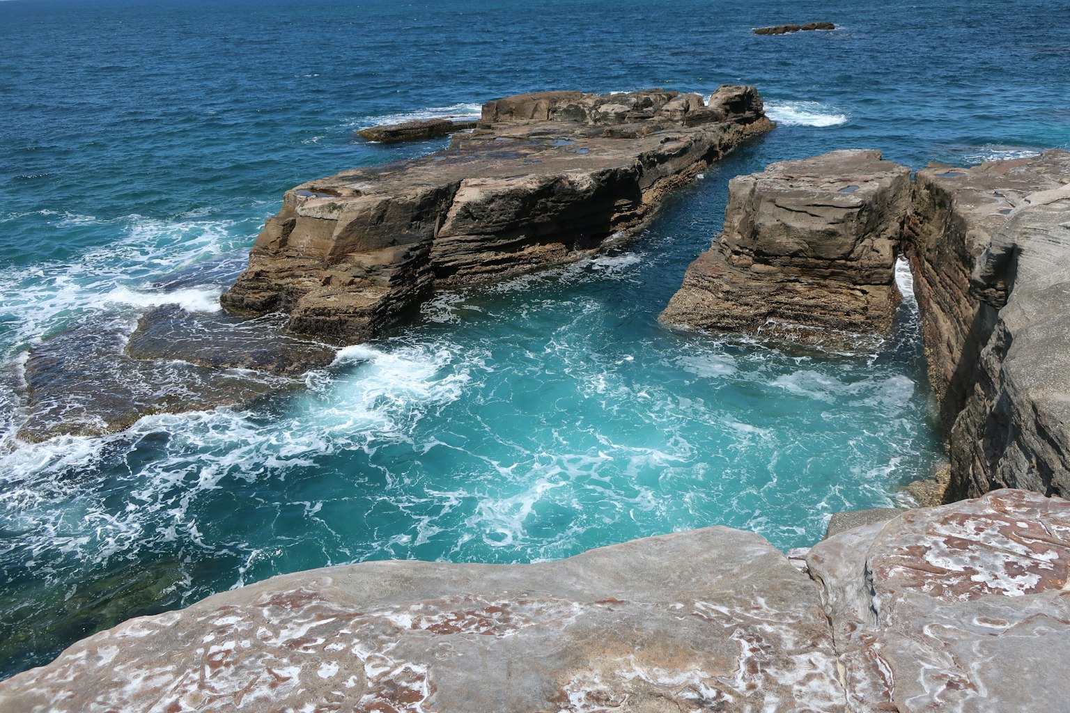 Des vagues se brisant entre des rochers dans un océan bleu