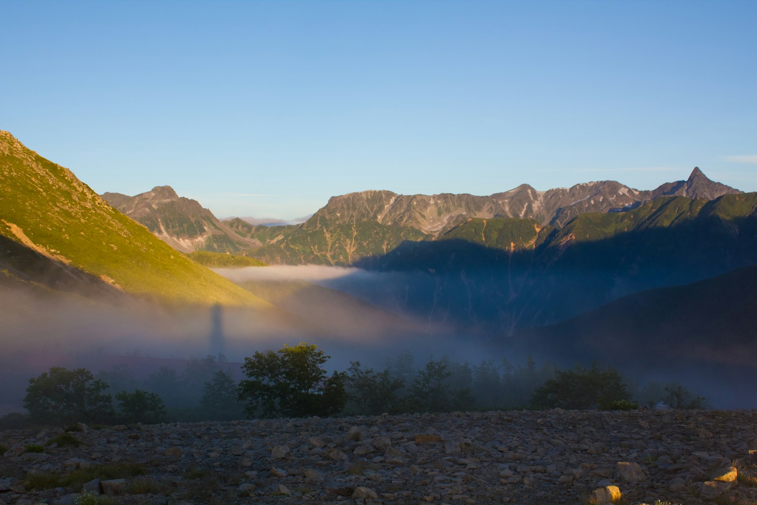 Paesaggio montano avvolto nella nebbia con cielo blu chiaro