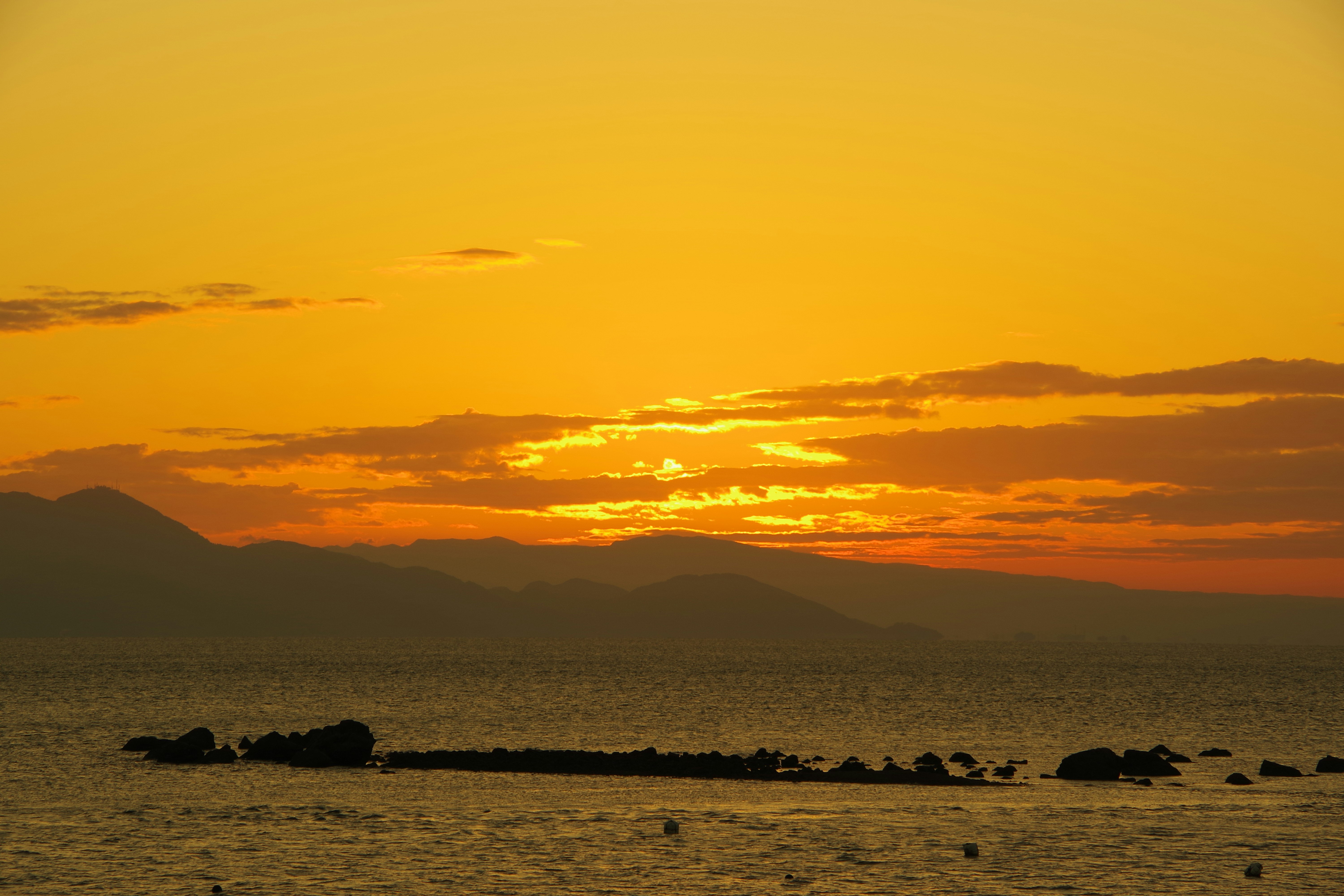 夕焼けの海辺に浮かぶ小島と水平線