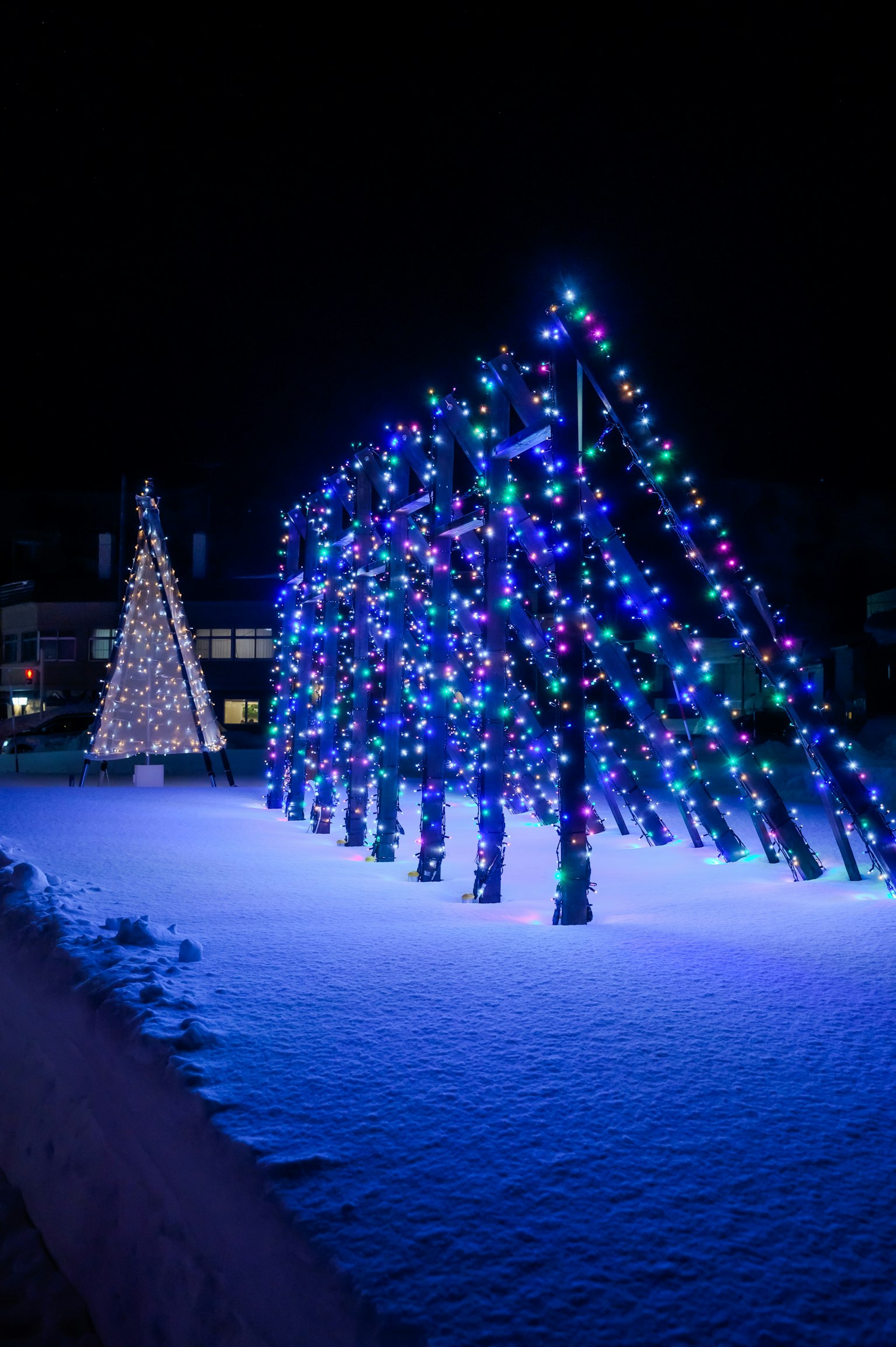 Scena notturna con albero di Natale e alberi illuminati di blu nella neve