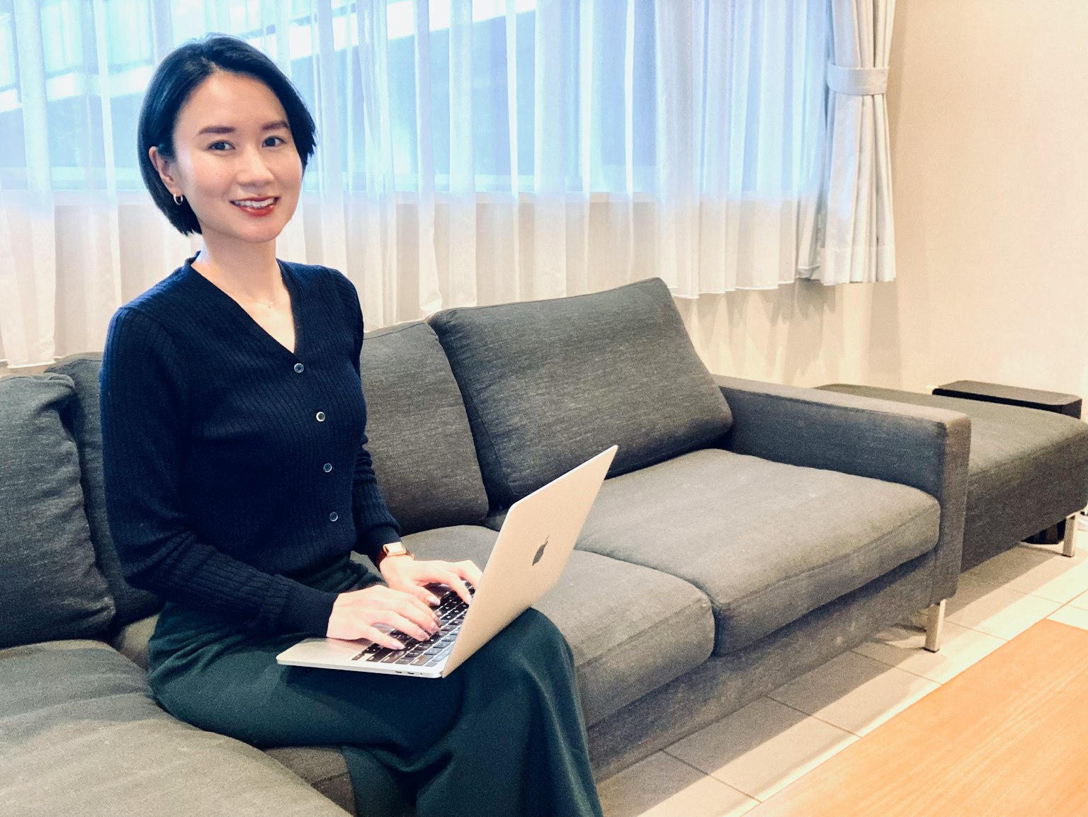 Une femme assise sur un canapé utilisant un ordinateur portable
