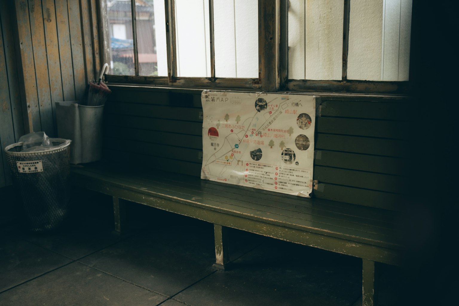 Panchina di legno vicino a una finestra con un poster colorato esposto