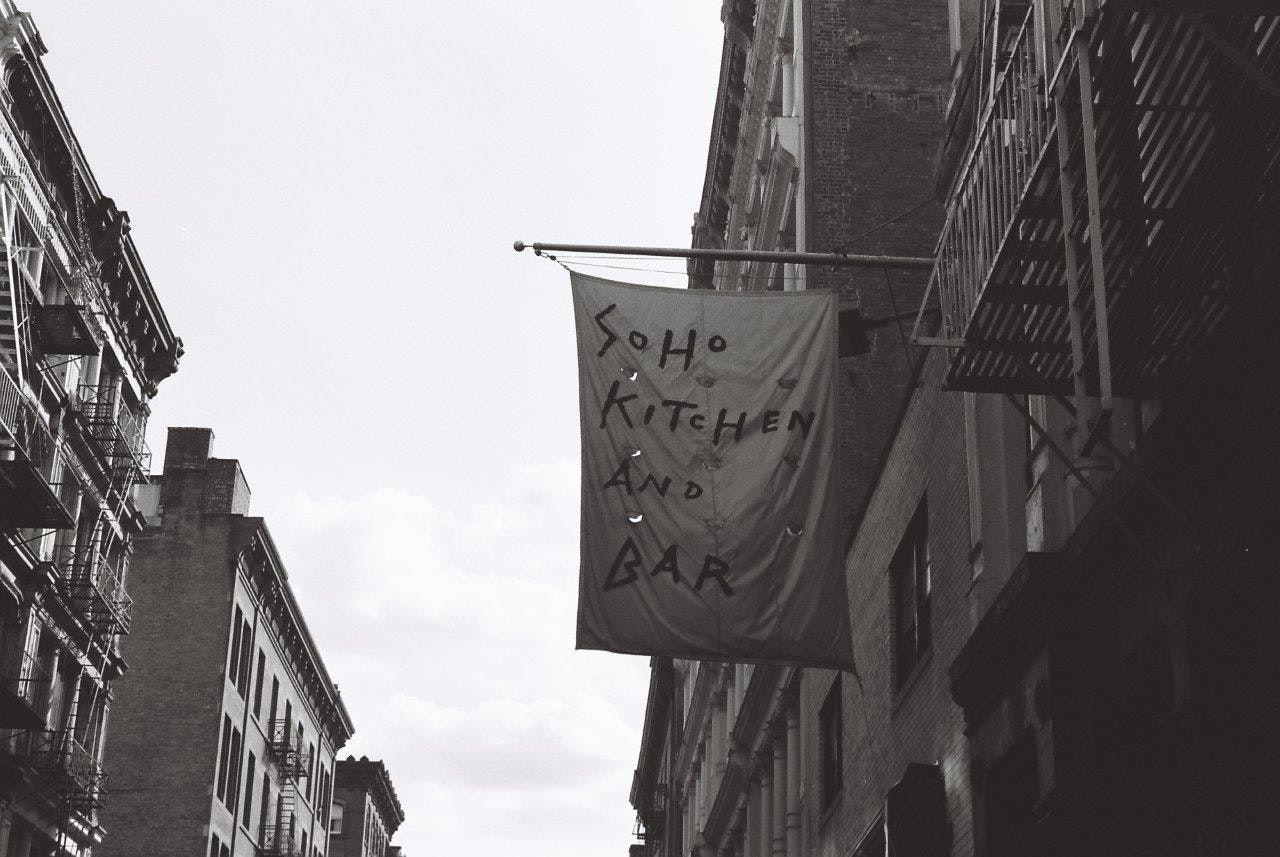 escena callejera con un cartel colgante “KITCHEN”
