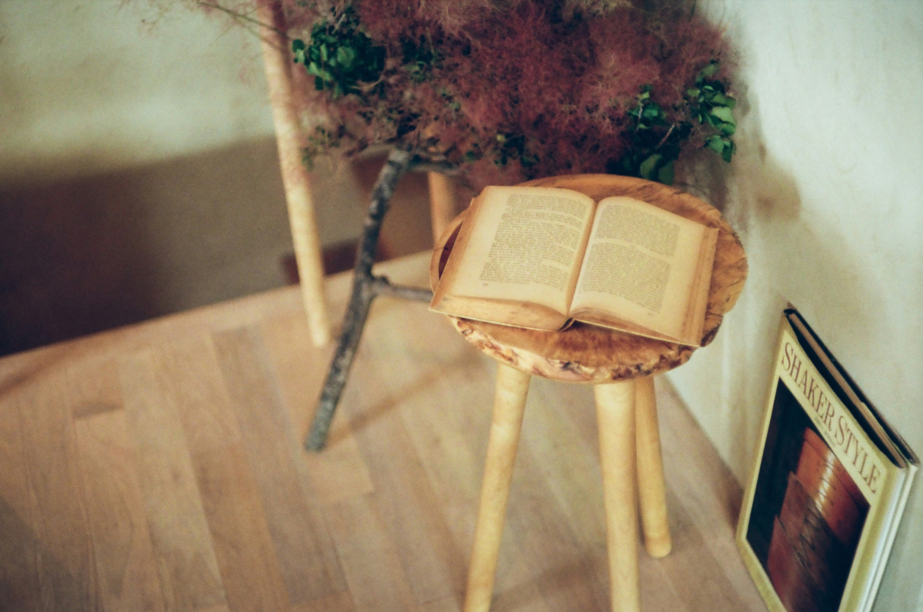 scène de lecture intérieure calme avec un livre ouvert sur un petit tabouret et un ancien magazine