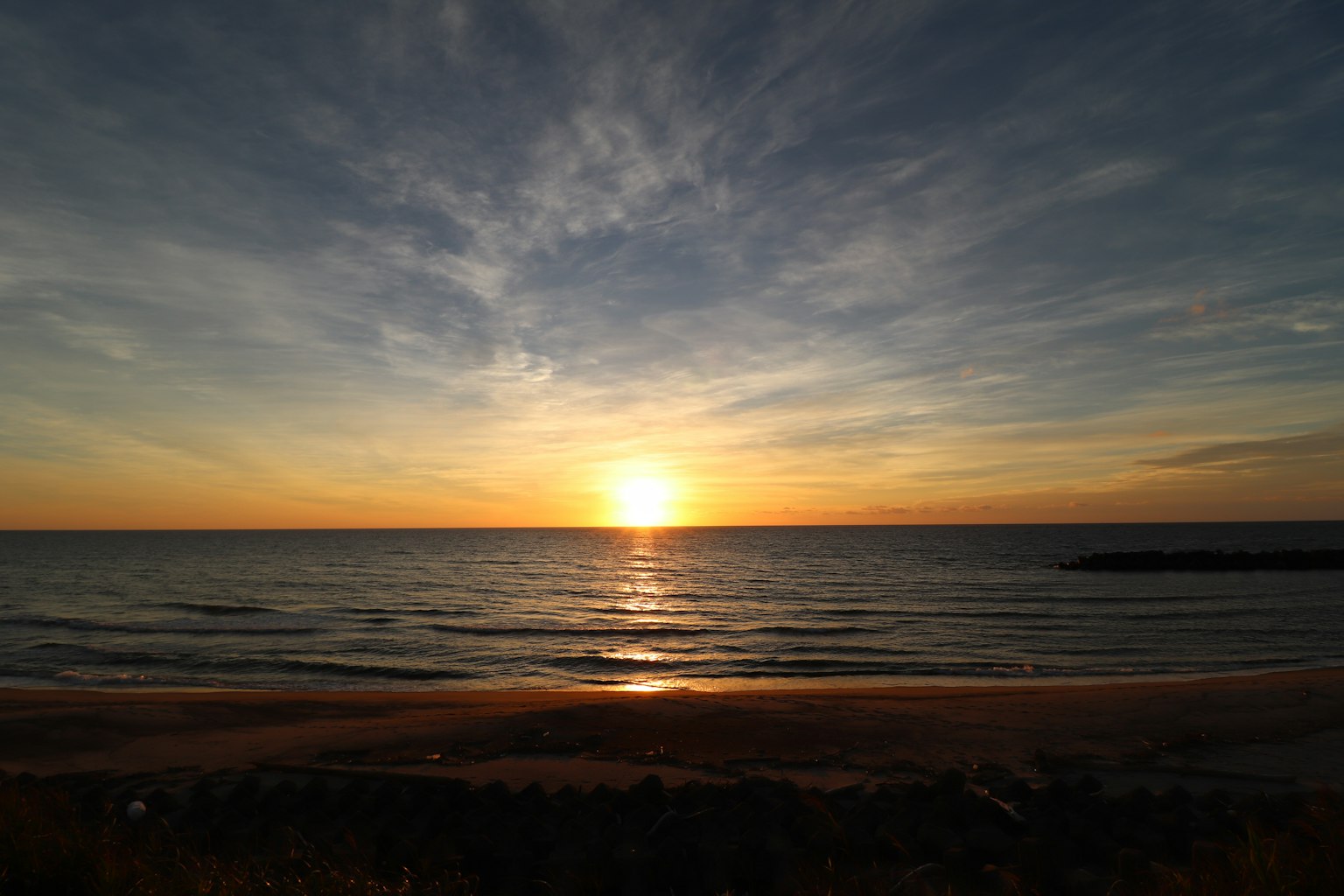 Beautiful sunset over the ocean with blue sky and orange clouds