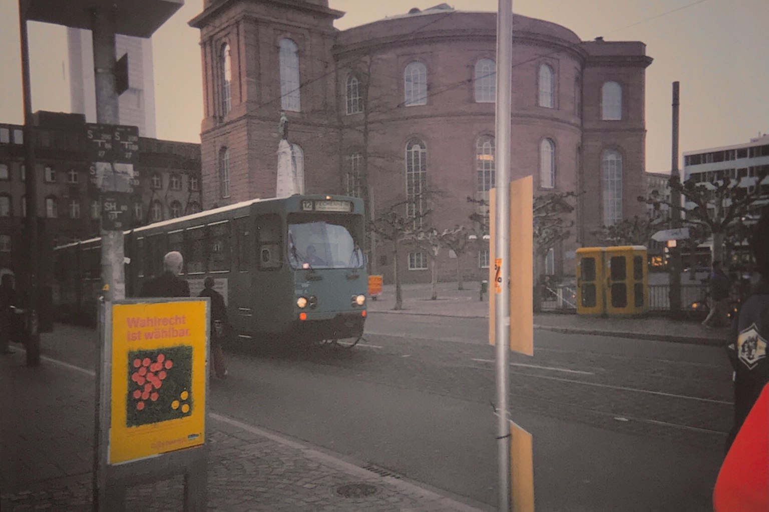 綠色公車在街角轉彎，背景是歷史建築
