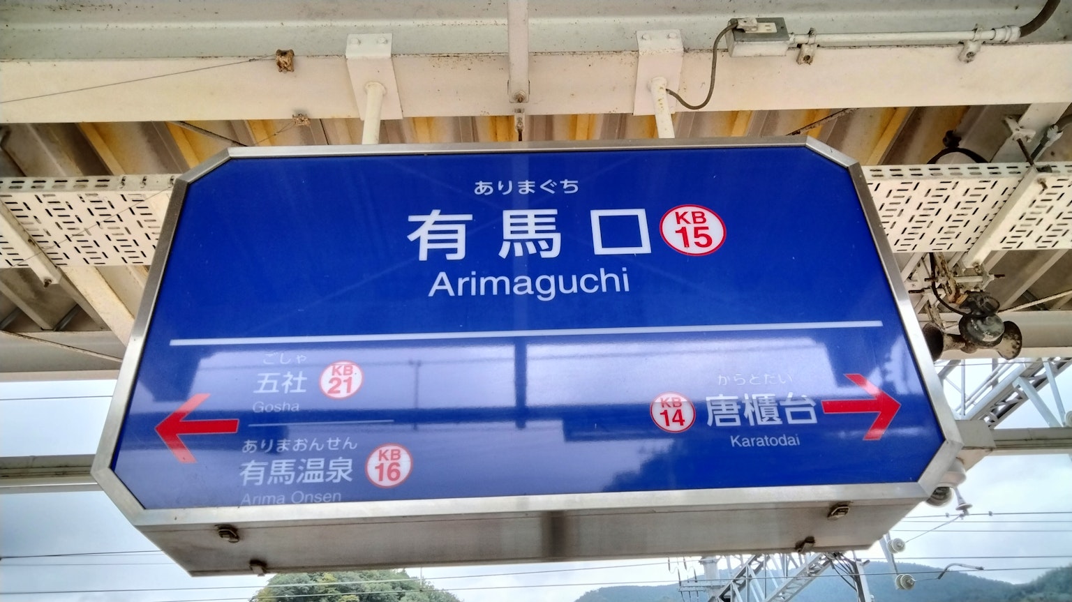 Tanda untuk Stasiun Arimaguchi dengan latar belakang biru dan teks putih