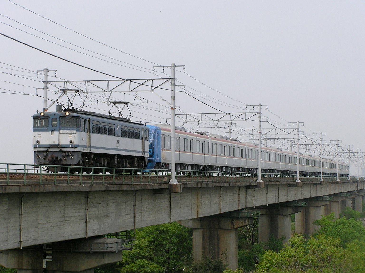 Train running on a bridge with green landscape