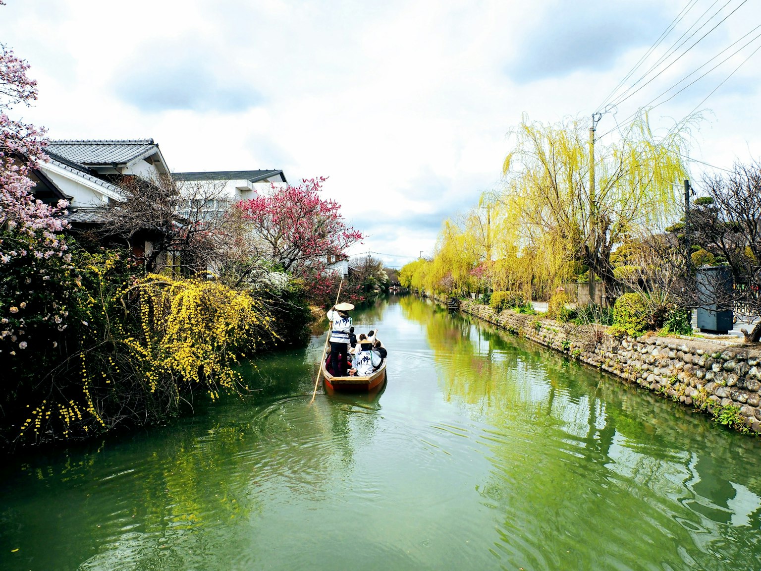 Vista primaveral escénica de un bote deslizándose por un canal tranquilo bordeado de árboles en flor