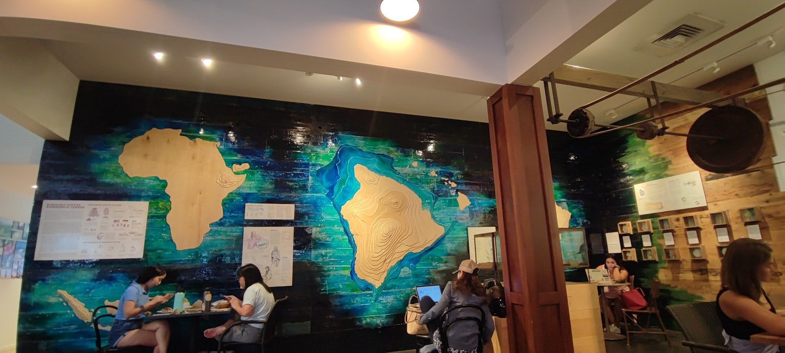 Interno di un caffè con un murale delle mappe dell'Africa e delle Hawaii