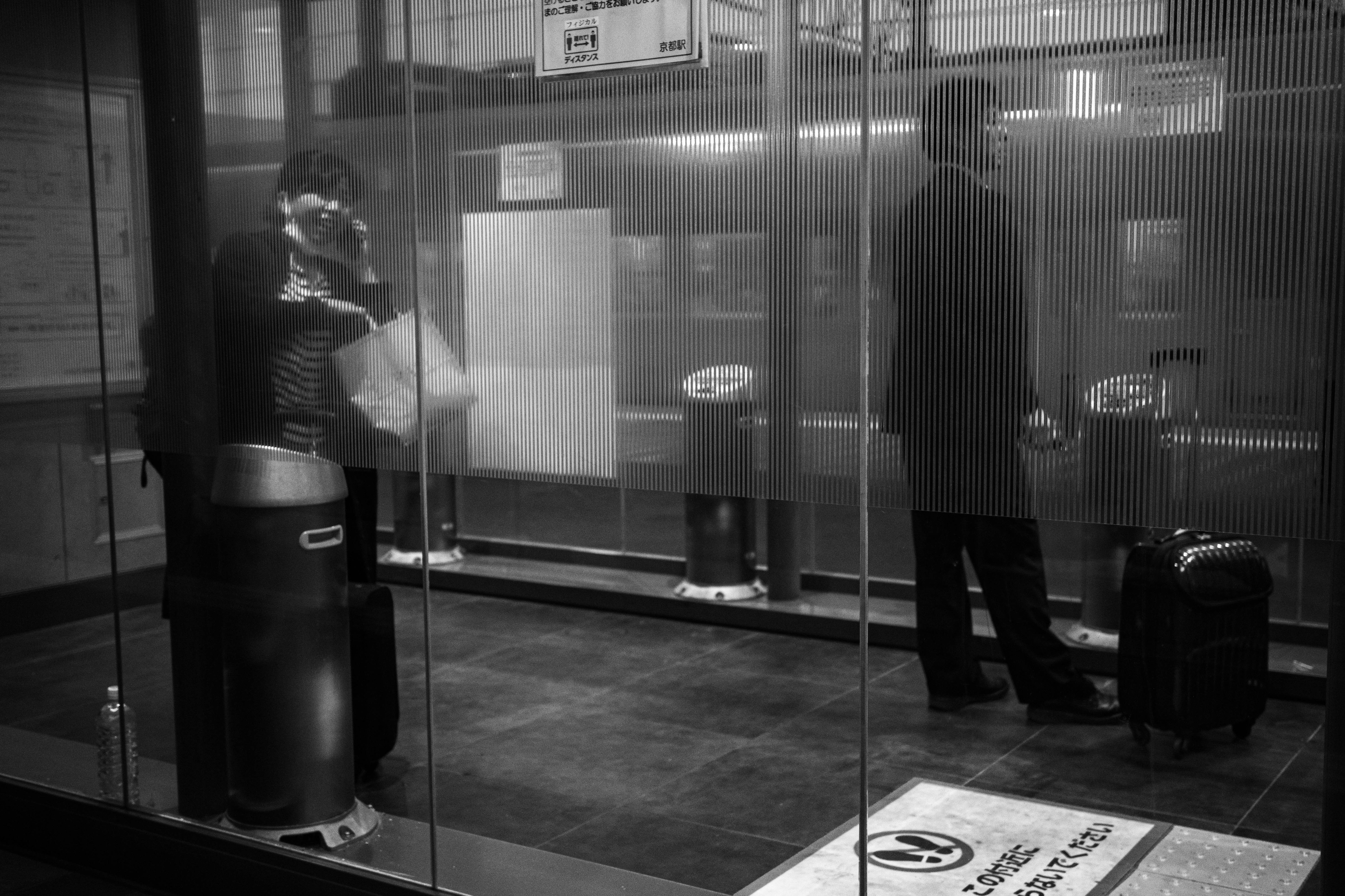 persona vicino ai tornelli della stazione davanti a un’area d’attesa vetrata