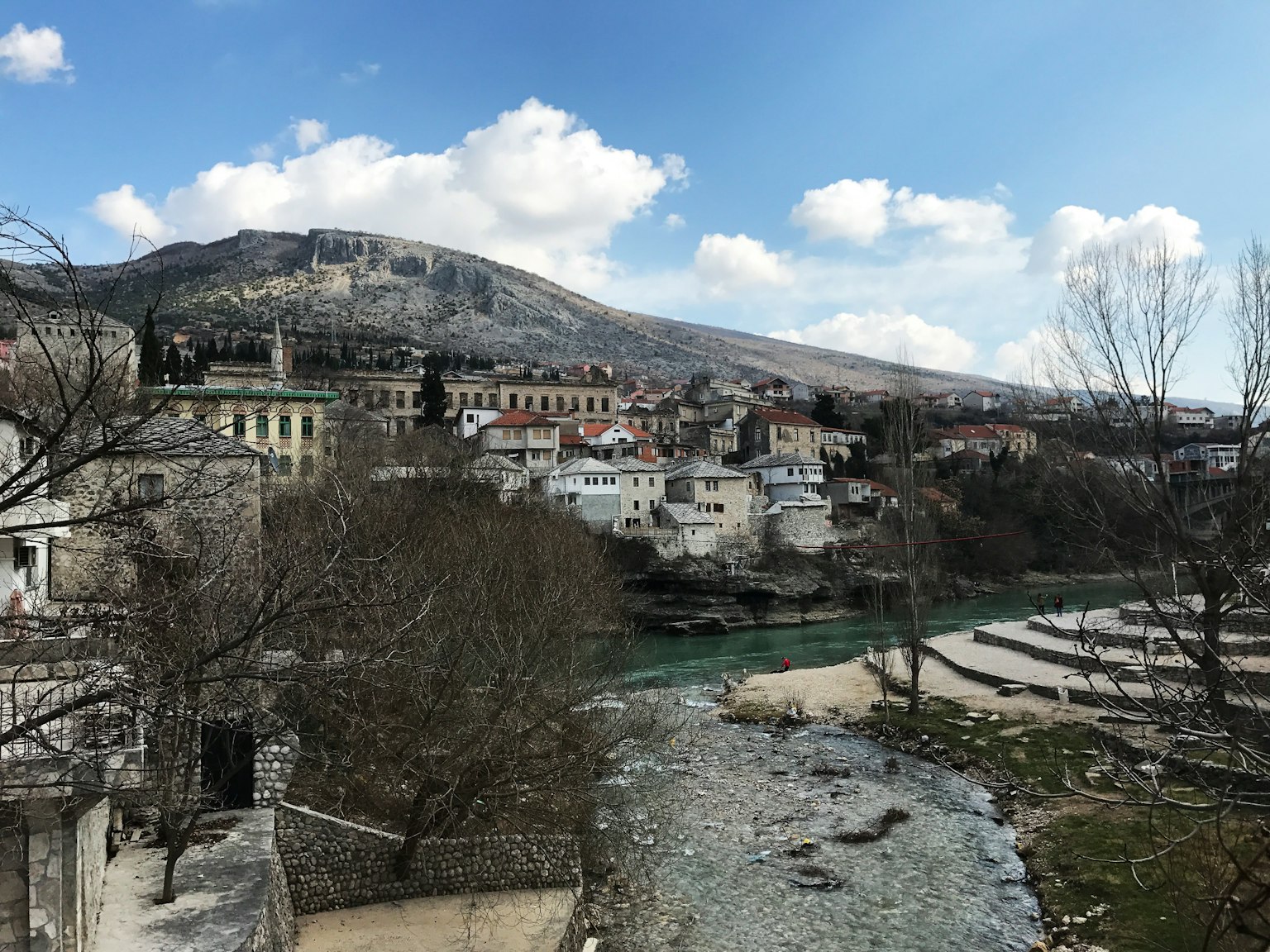 Scenic view of a small town by a river with mountains in the background