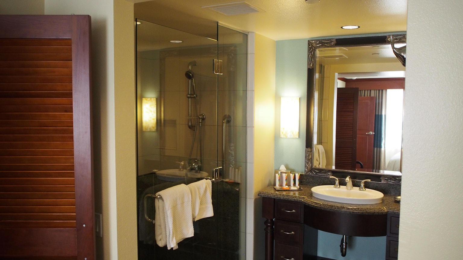 Interno di bagno moderno con doccia in vetro, lavandino, asciugamani e armadietto in legno