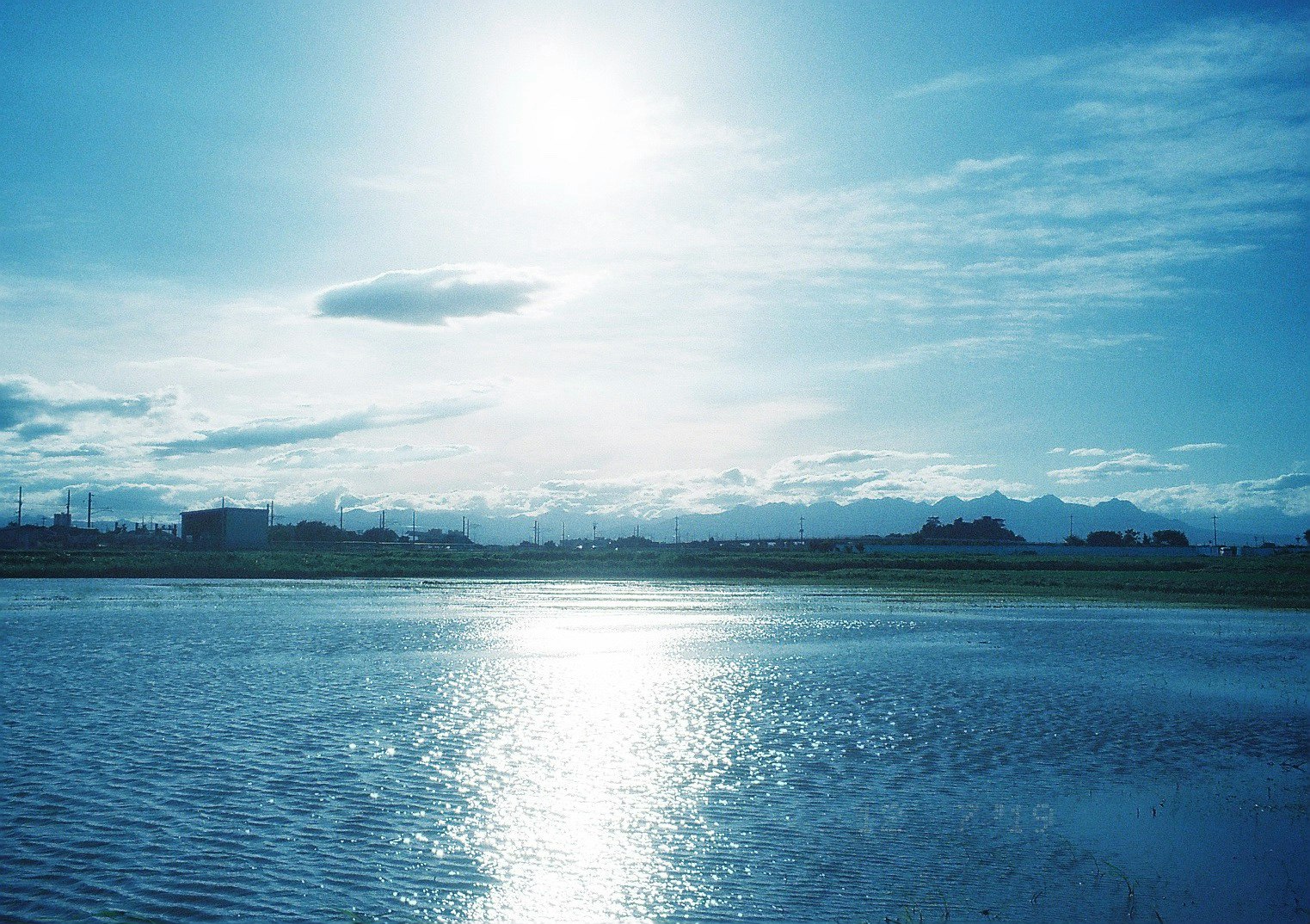 luce del mattino riflessa su un fiume con skyline industriale lontano
