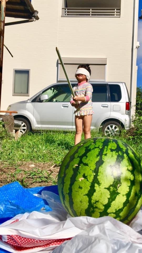 スイカ割りの準備中、庭先に置かれた大きなスイカと子ども