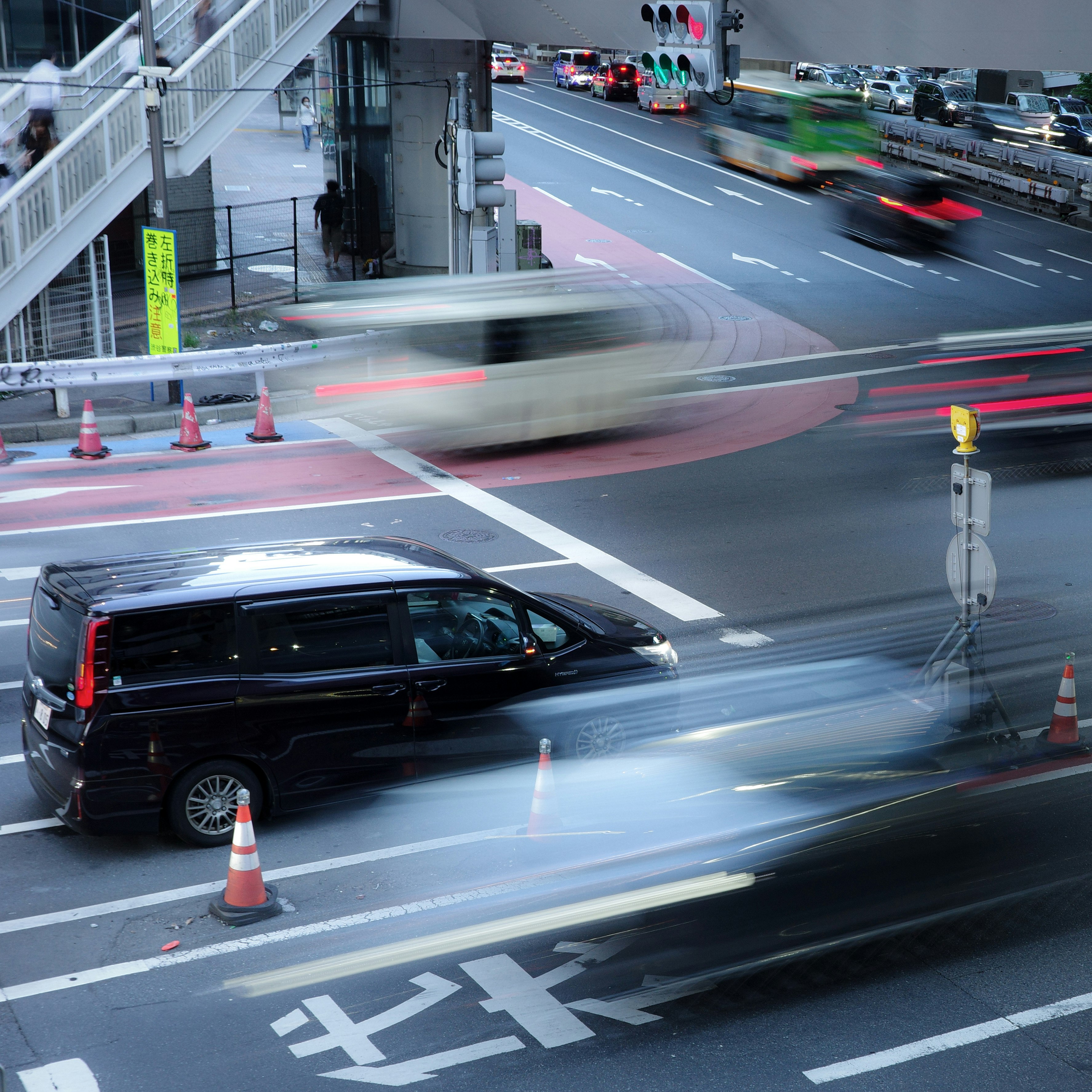 交差点を走る車の流れと横断歩道のある街並み
