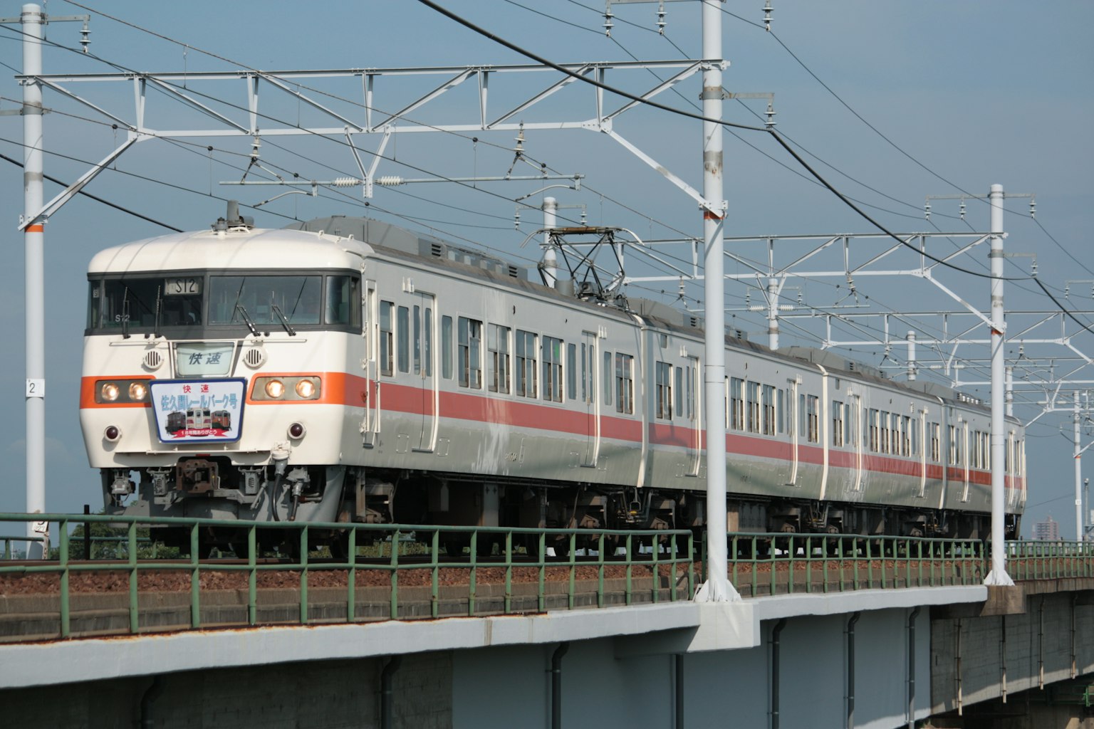 白色和橙色條紋的火車在高架軌道上行駛