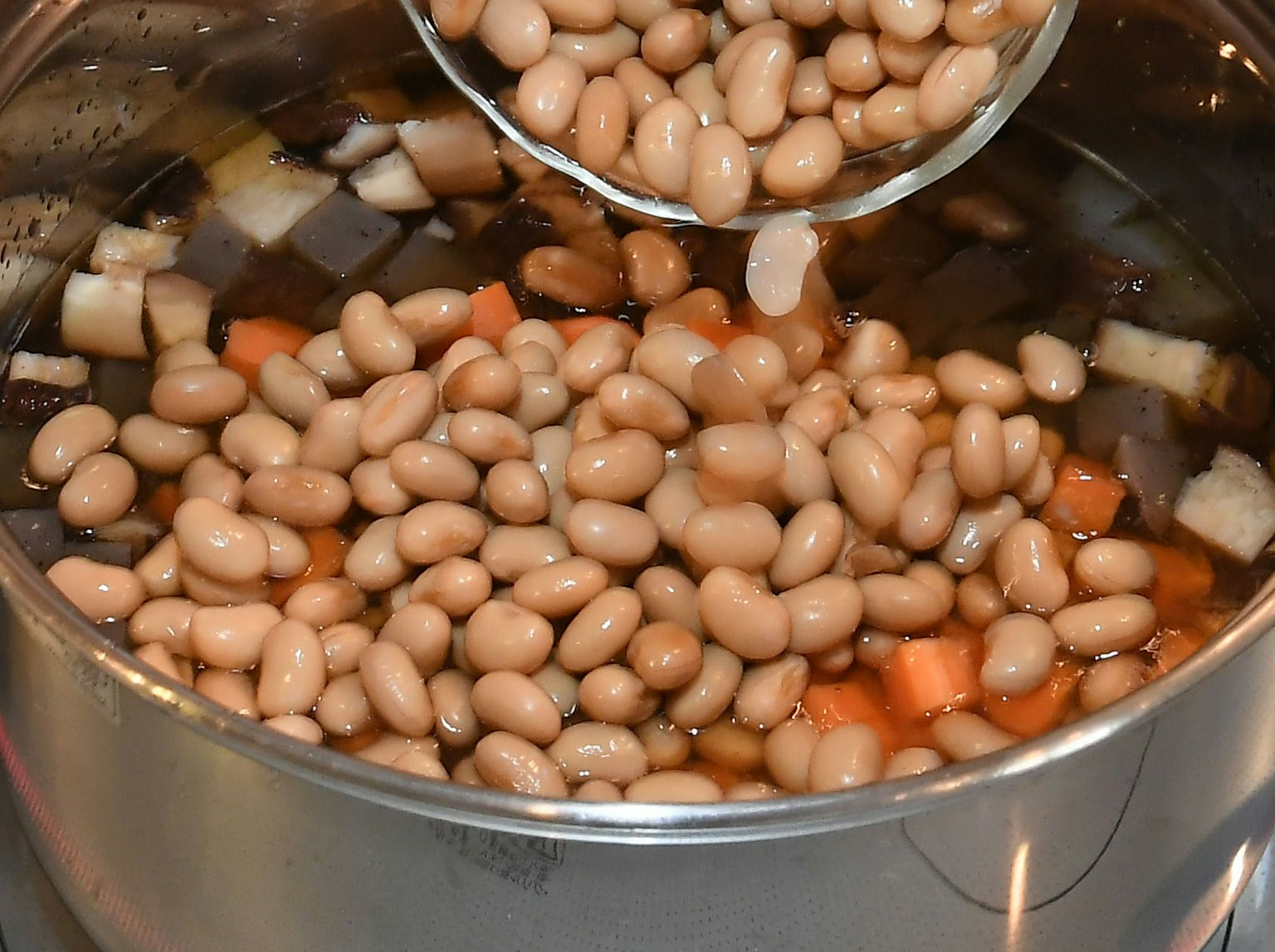 Una pentola piena di fagioli e verdure in brodo