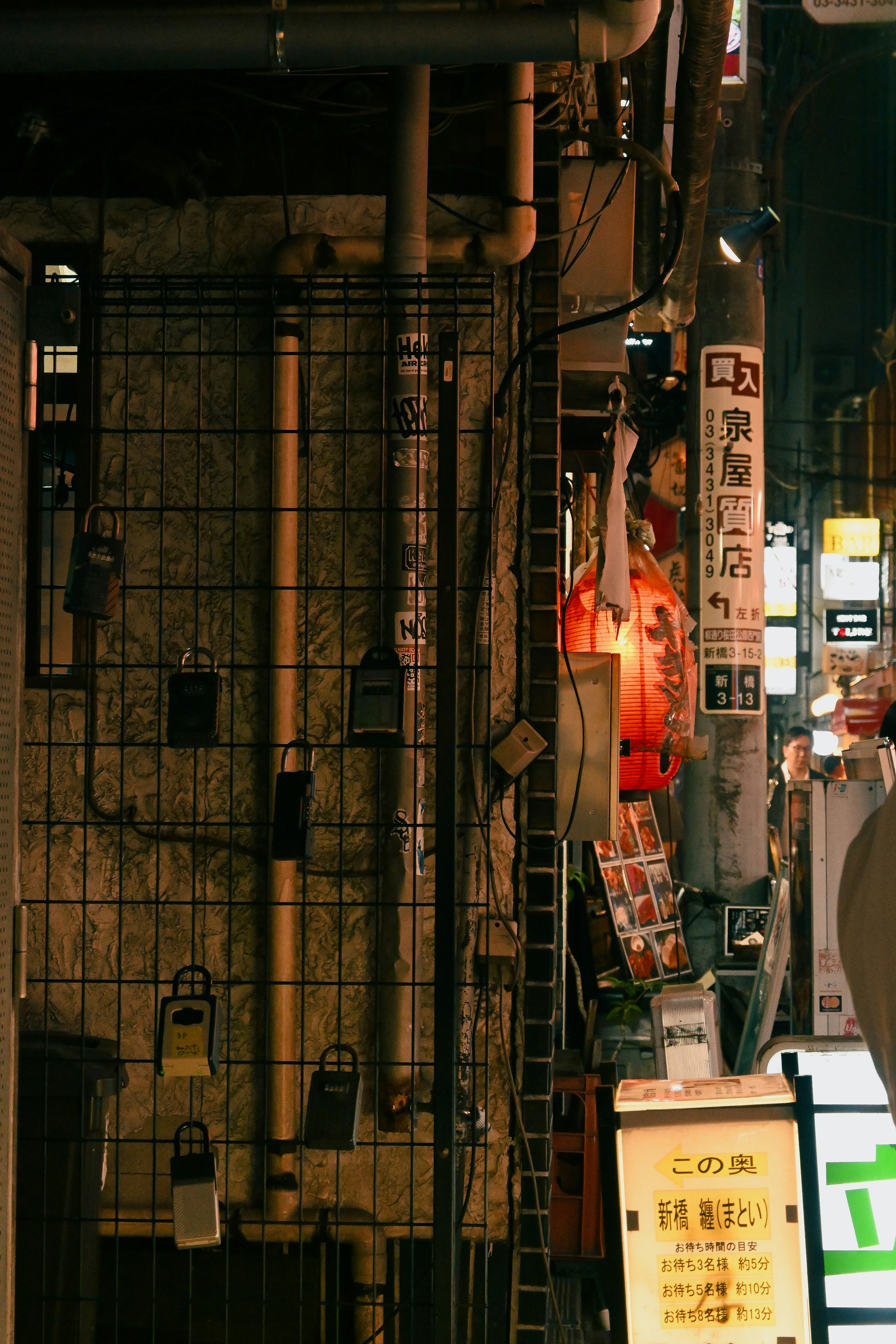 路地の金属フェンスと提灯のある小さな店先