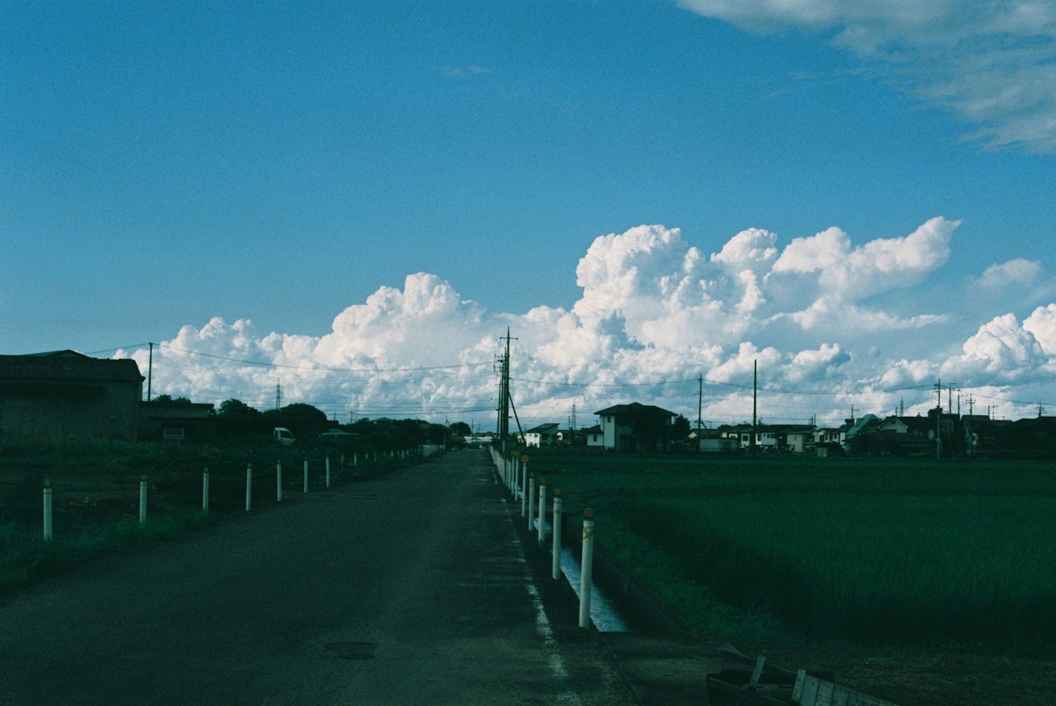 Countryside road under blue sky with fluffy white clouds