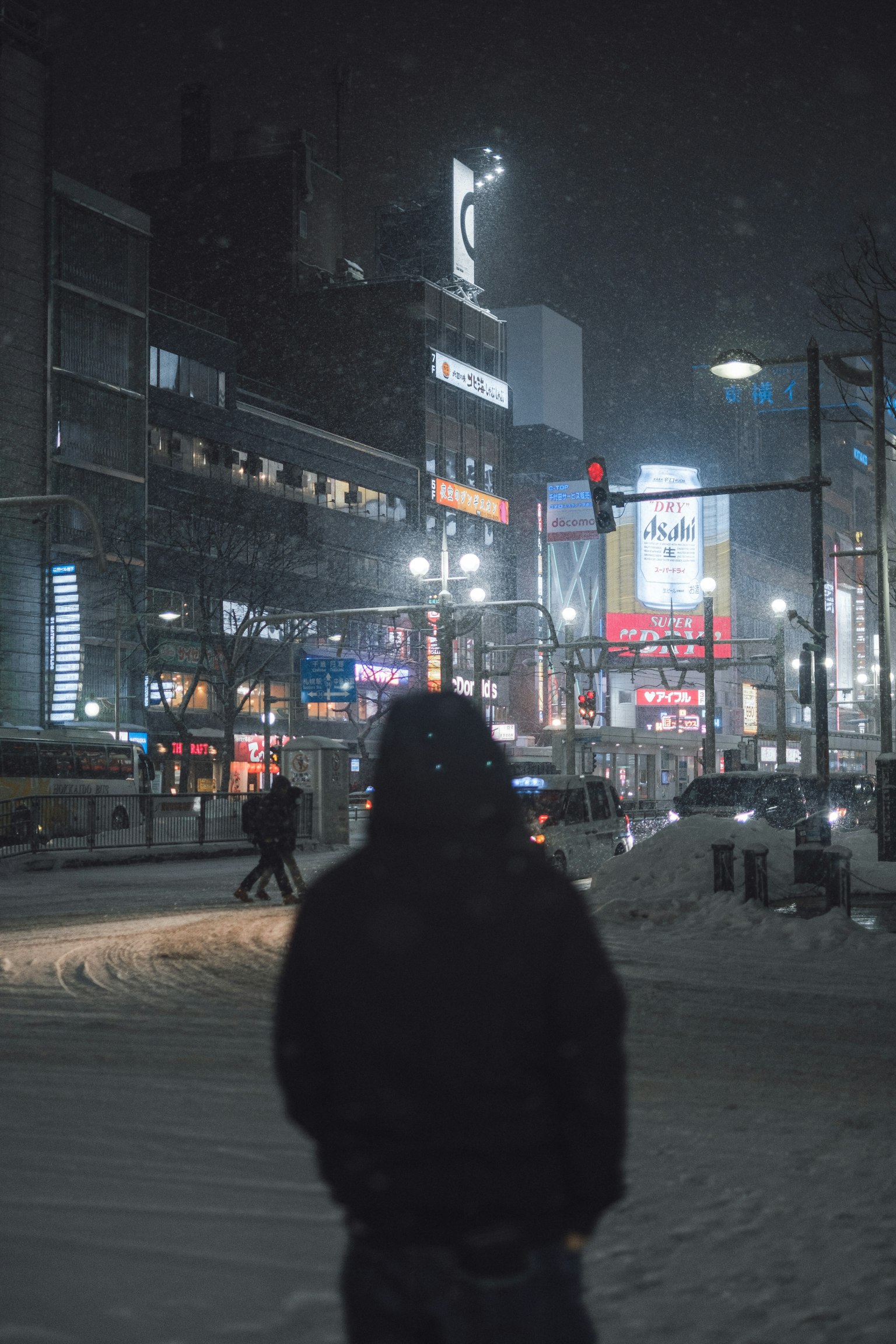 在雪夜城市中站着的人与明亮的广告牌