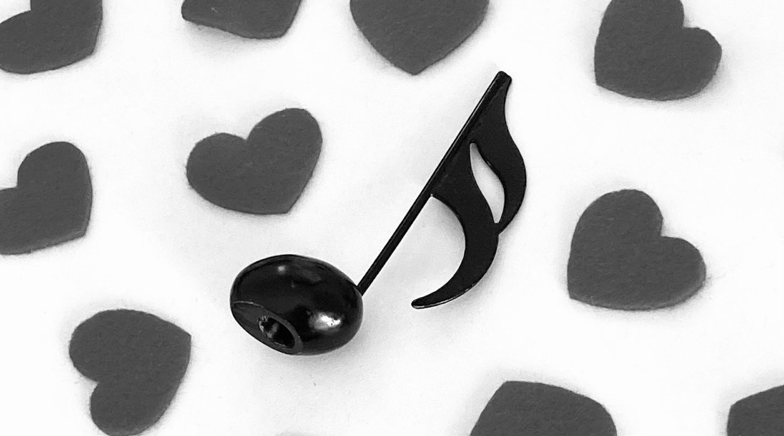Una nota musical negra rodeada de corazones dispersos sobre un fondo blanco