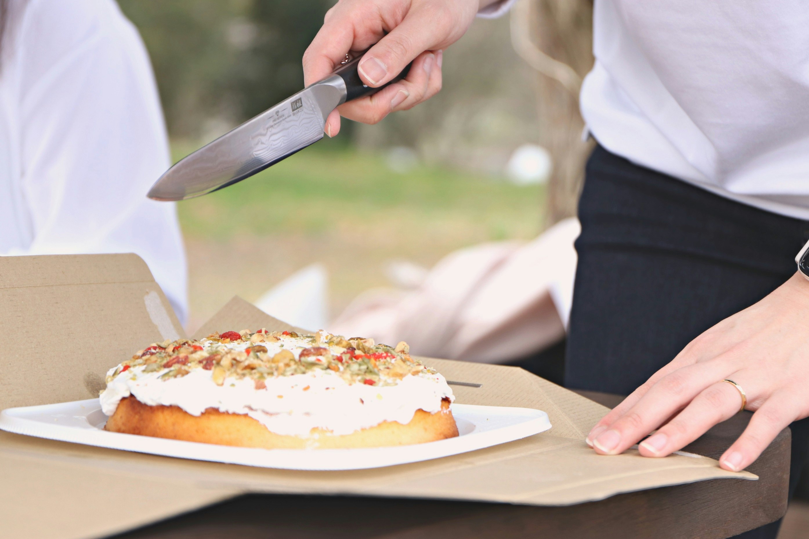 Hände servieren ein Stück Kuchen im Freien