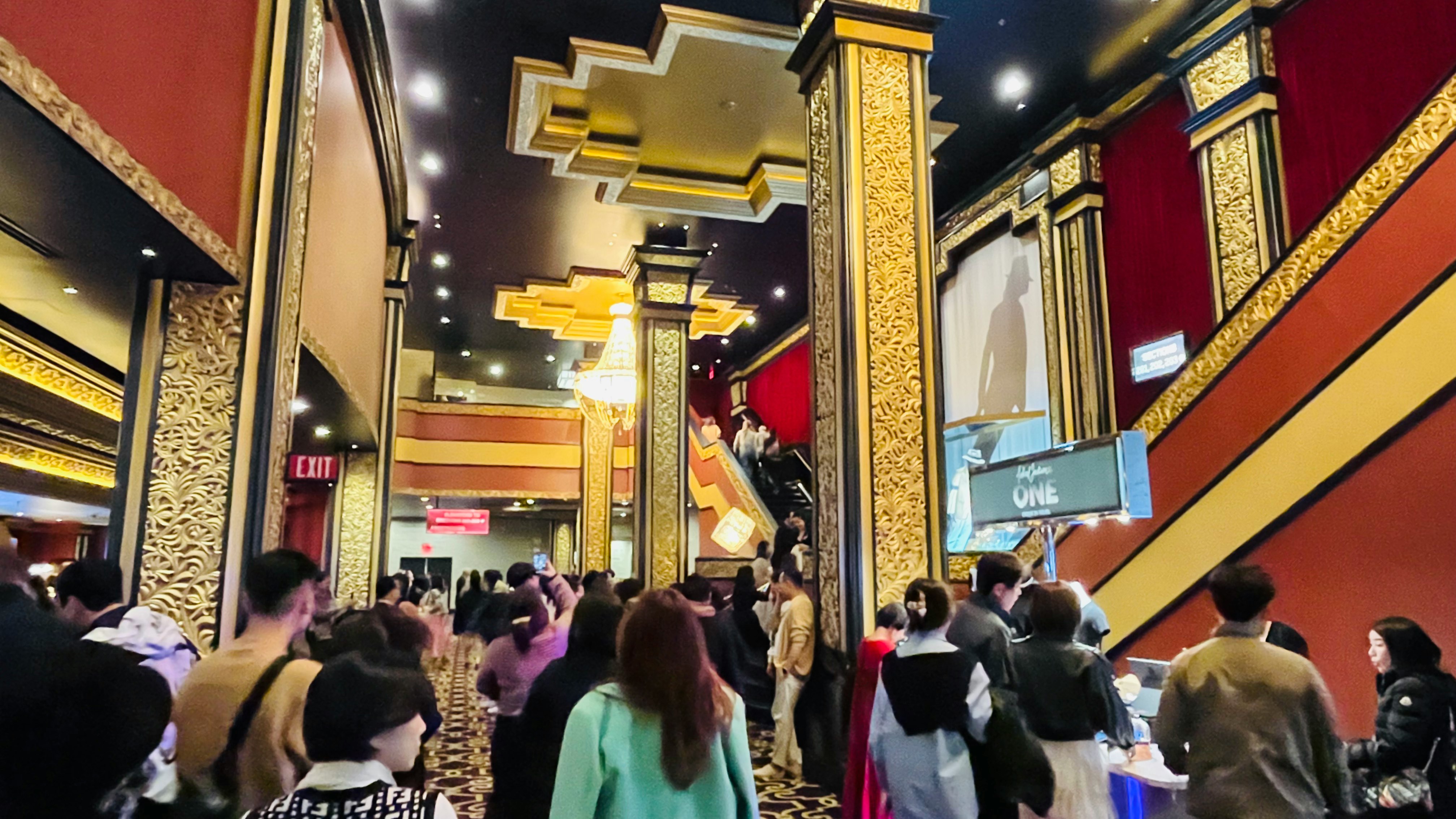 People walking through an indoor corridor with red and gold decorative columns