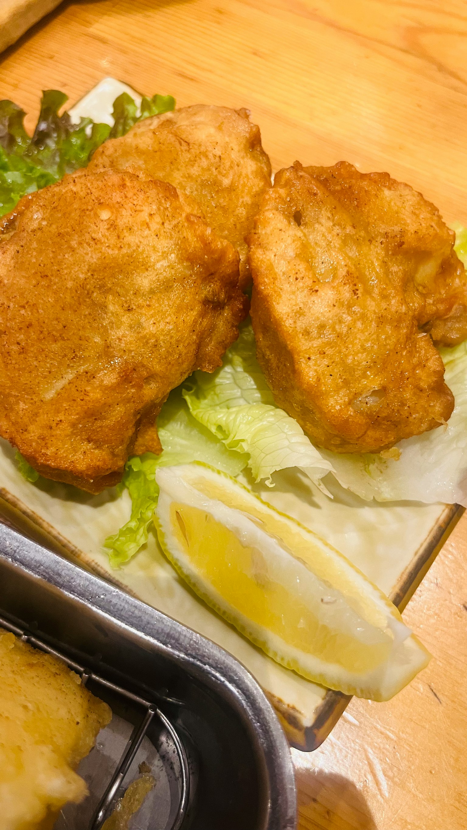 炸魚片放在生菜上，旁邊有一片檸檬