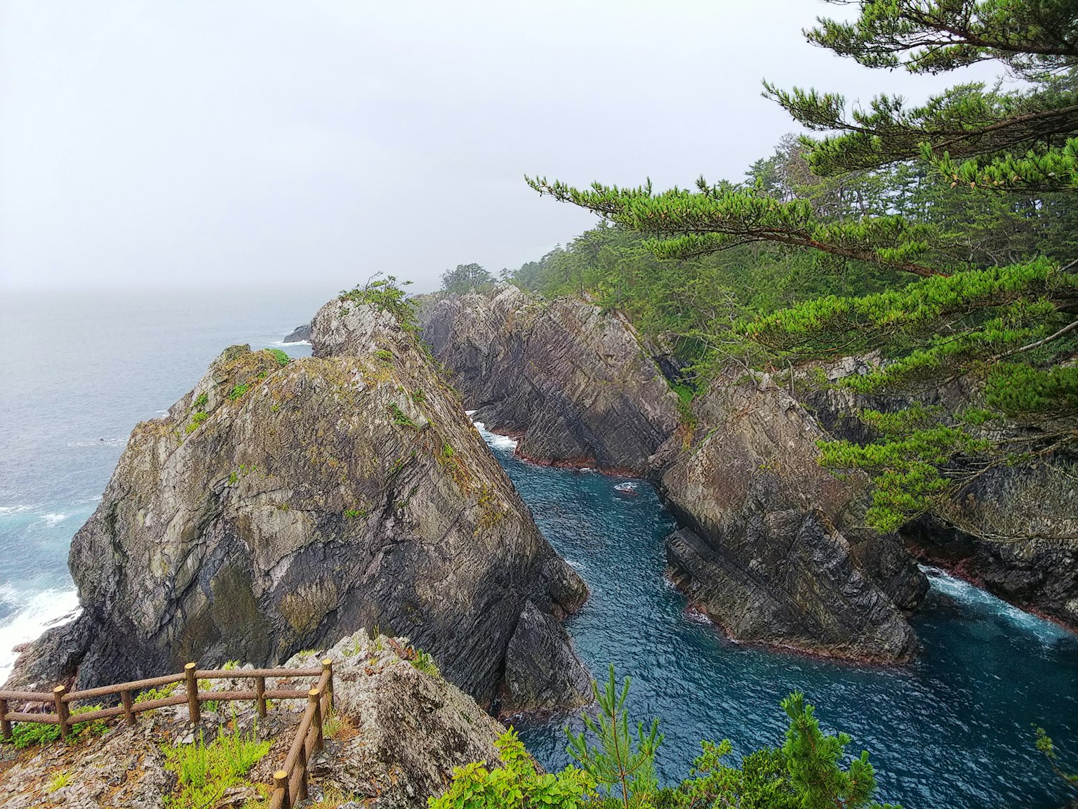 雾蒙蒙的海岸景观，岩石悬崖和蓝色海洋