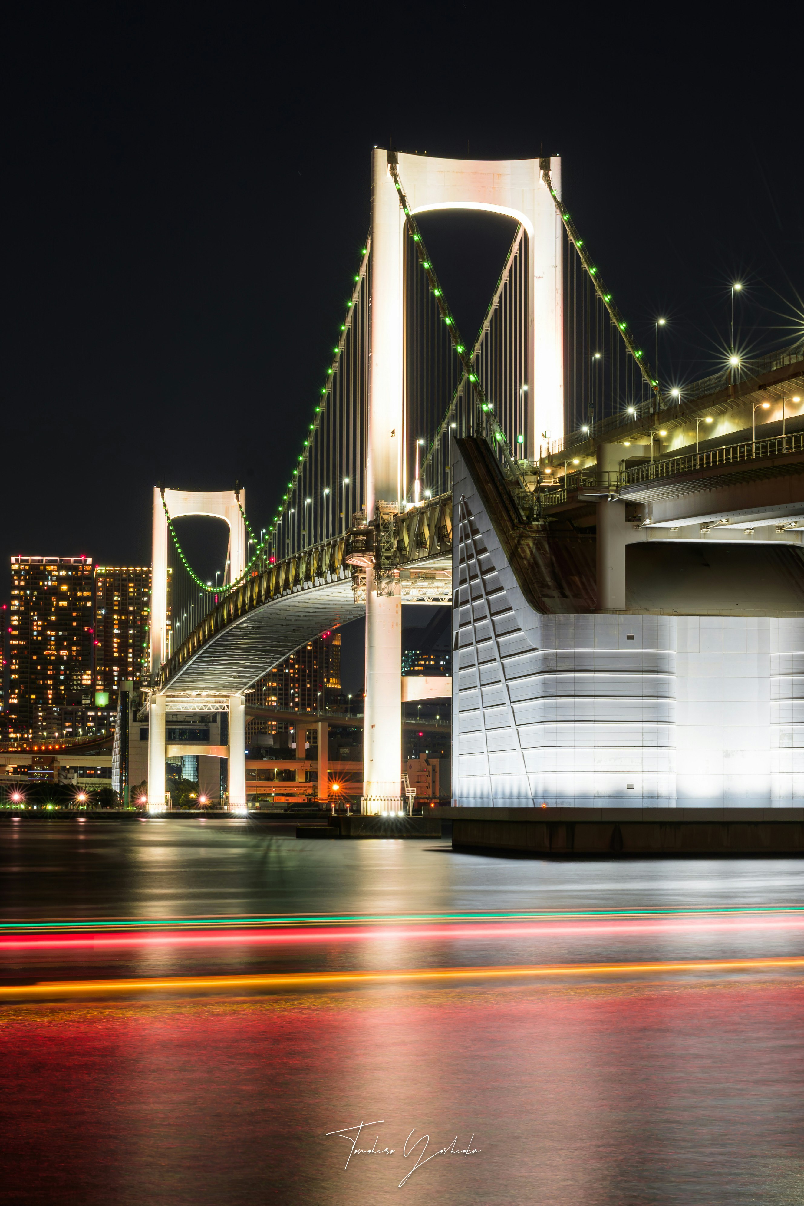 レインボーブリッジと台場公園の夜景、雨上がりの水面に光がにじむ