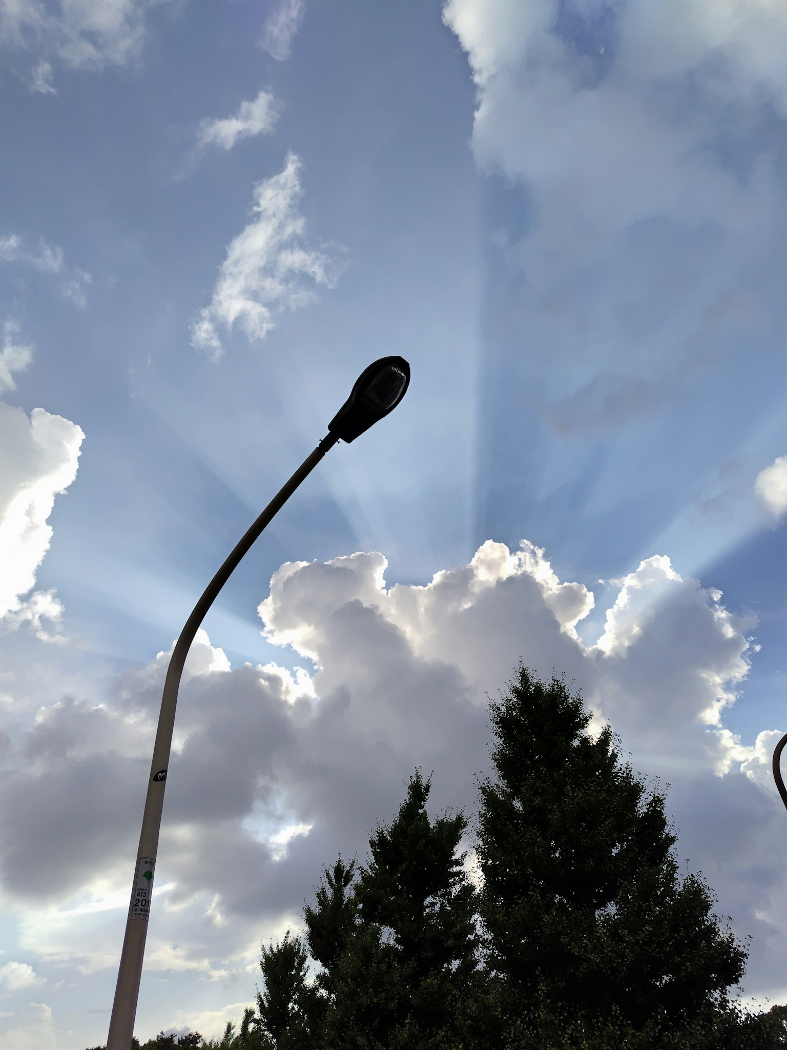 Farola con rayos de luz que atraviesan las nubes