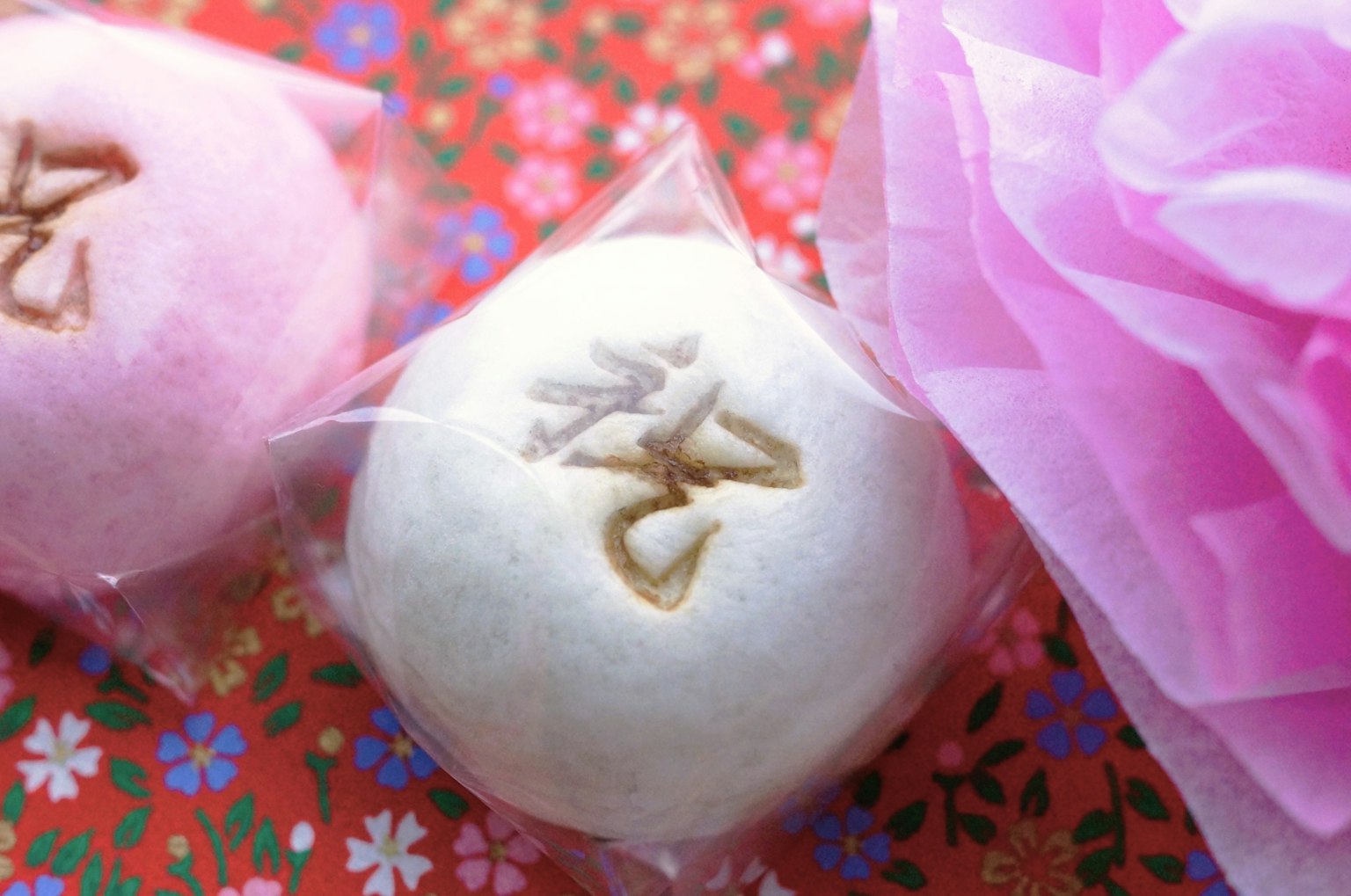 Bánh ngọt Nhật Bản màu trắng và hồng được bọc trong bao bì trong suốt trên nền hoa