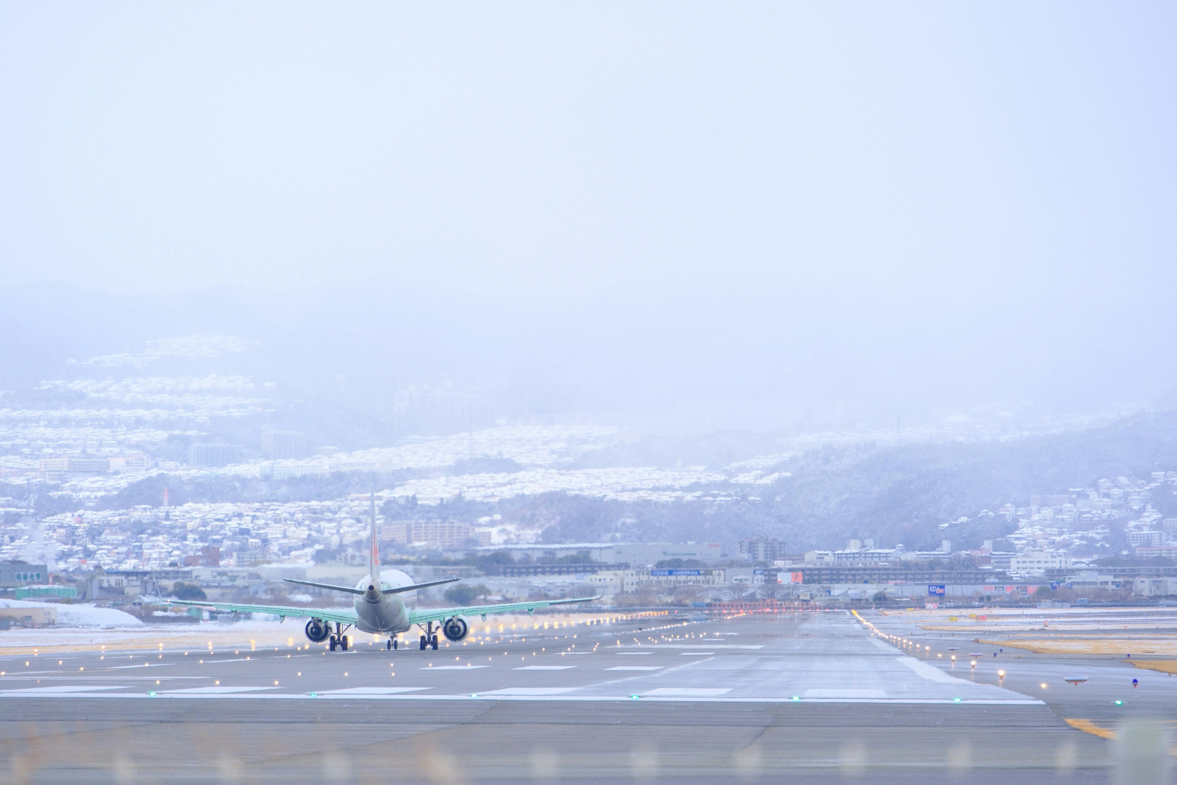 雪に覆われた滑走路に停まる航空機と遠くの山々