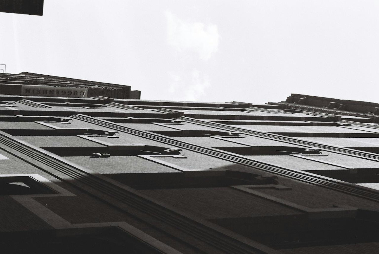 Monochromfoto eines Gebäudes von unten betrachtet Einzigartige Fensterformen und -anordnung