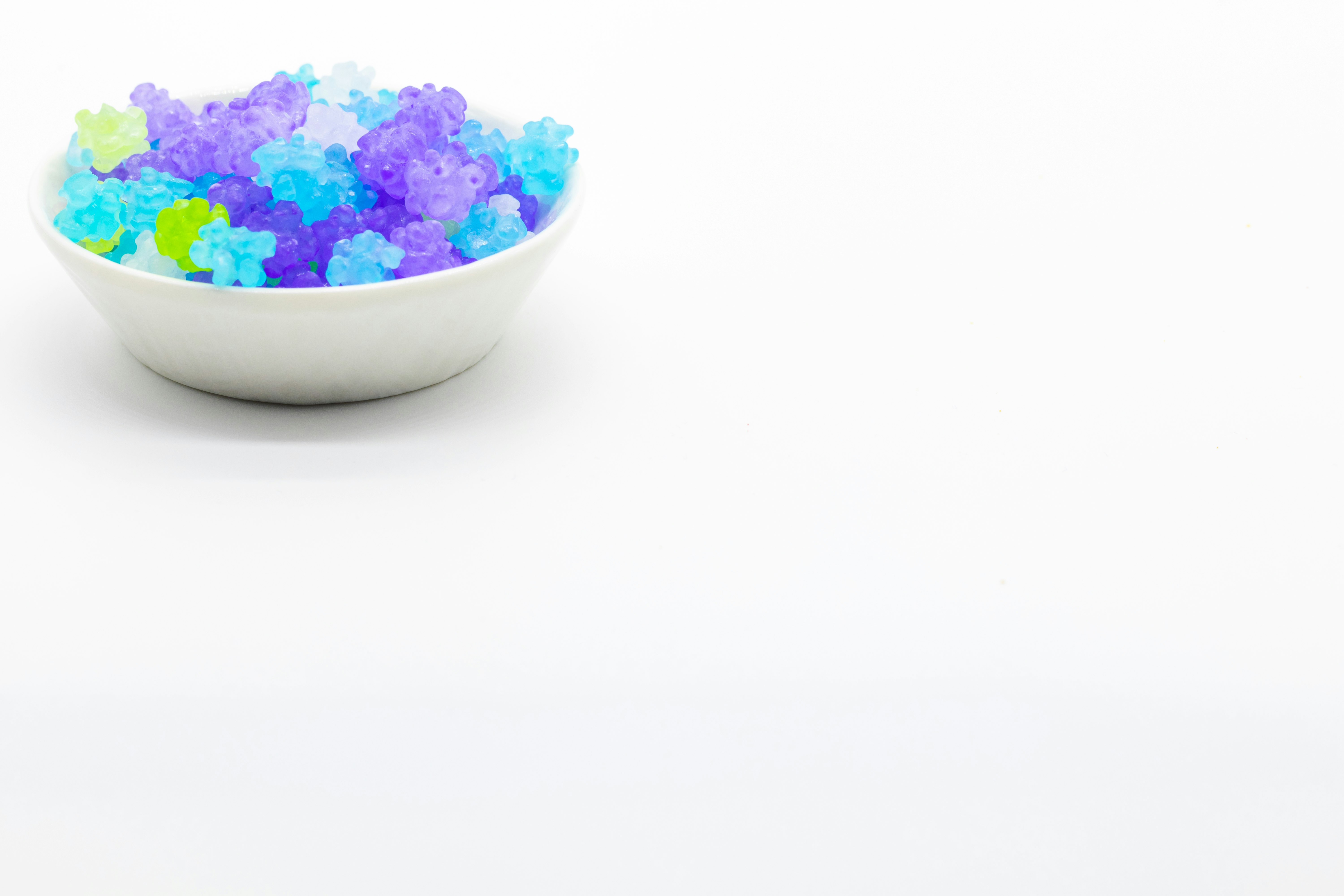 白い器に入った青紫の色付き砂糖菓子