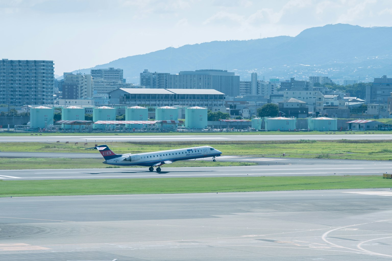 Airplane taxiing on runway with city skyline in background